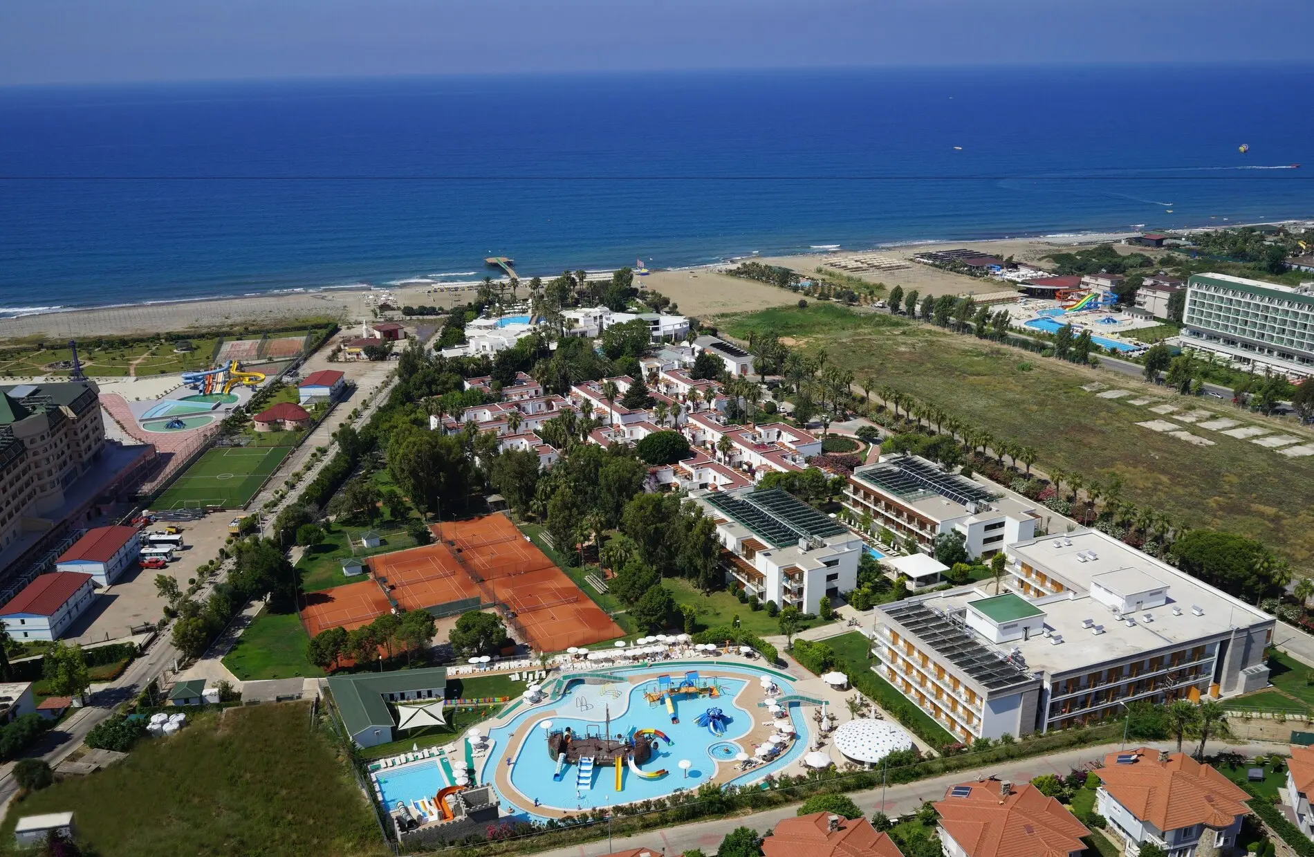 Панорамна снимка на комплекса край морето с басейн и тенис кортове – Club Kastalia Holiday Village, Алания