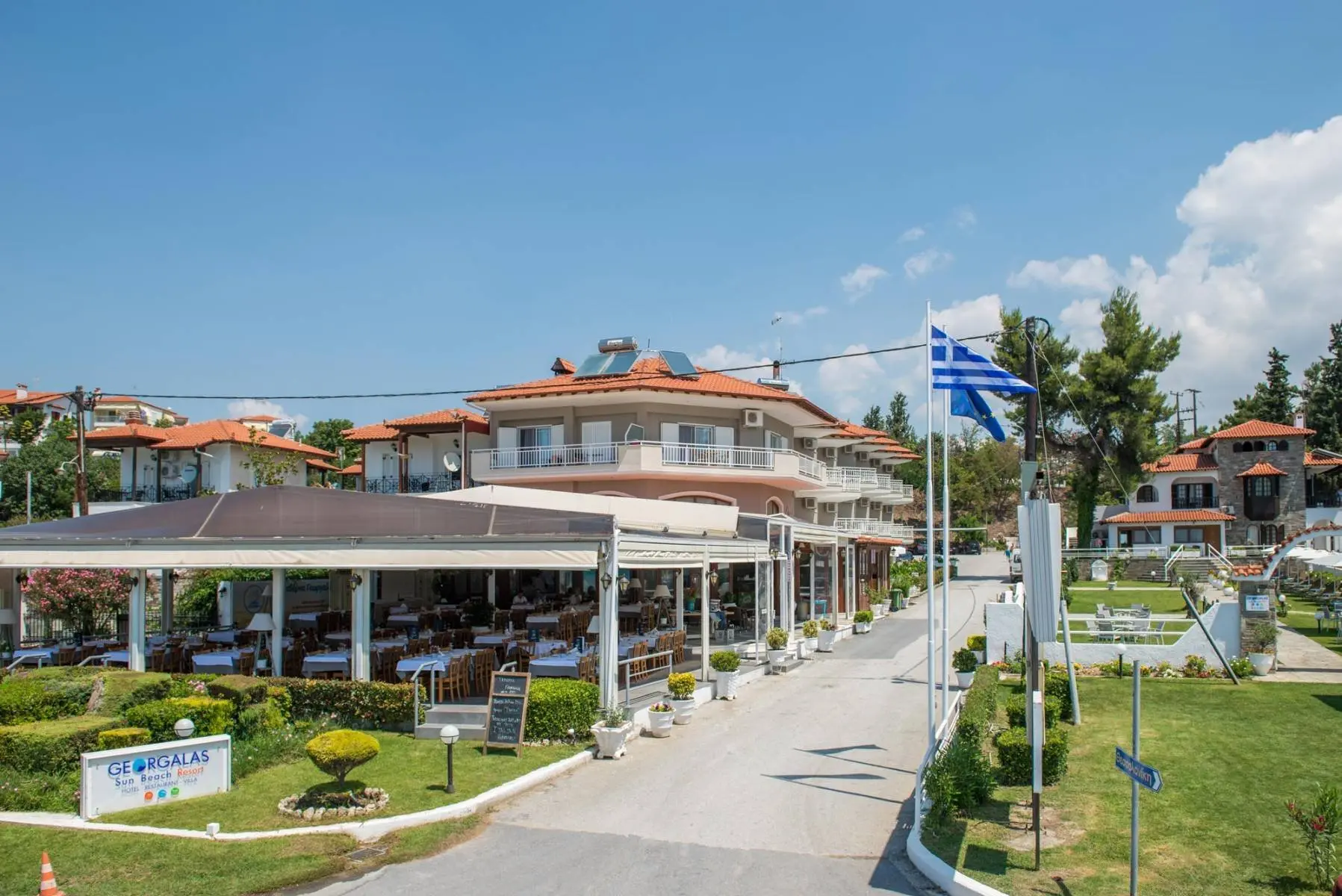 Хотелът с гръцко знаме, ресторант и градина пред него – Georgalas Sun Beach Hotel, Неа Каликратия