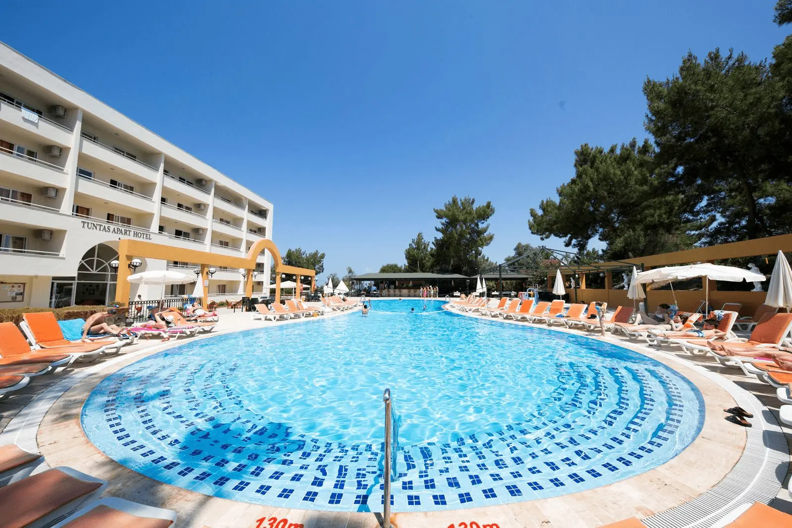 Кръгъл басейн с шезлонги пред хотелската сграда сред борове – Tuntas Beach Hotel, Дидим