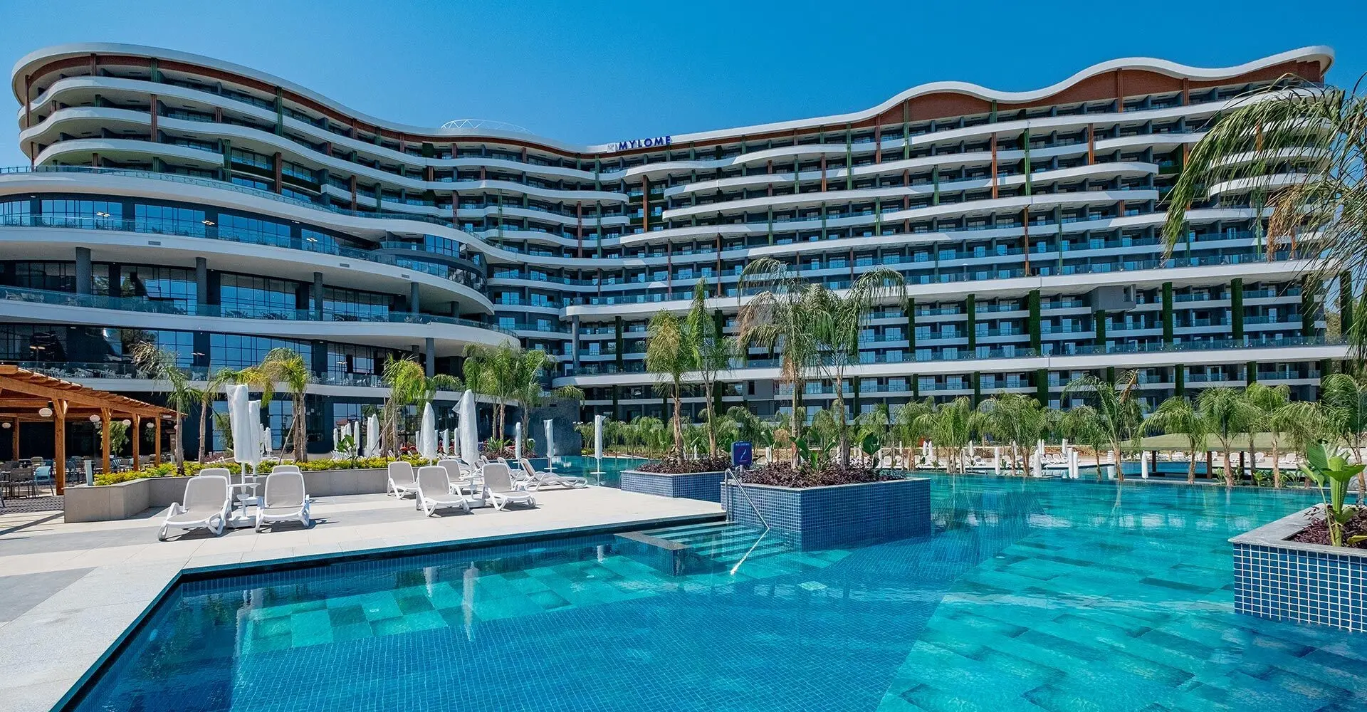 Извитата основна сграда с тераси и голям басейн отпред – Mylome Luxury Hotel & Resort, Алания