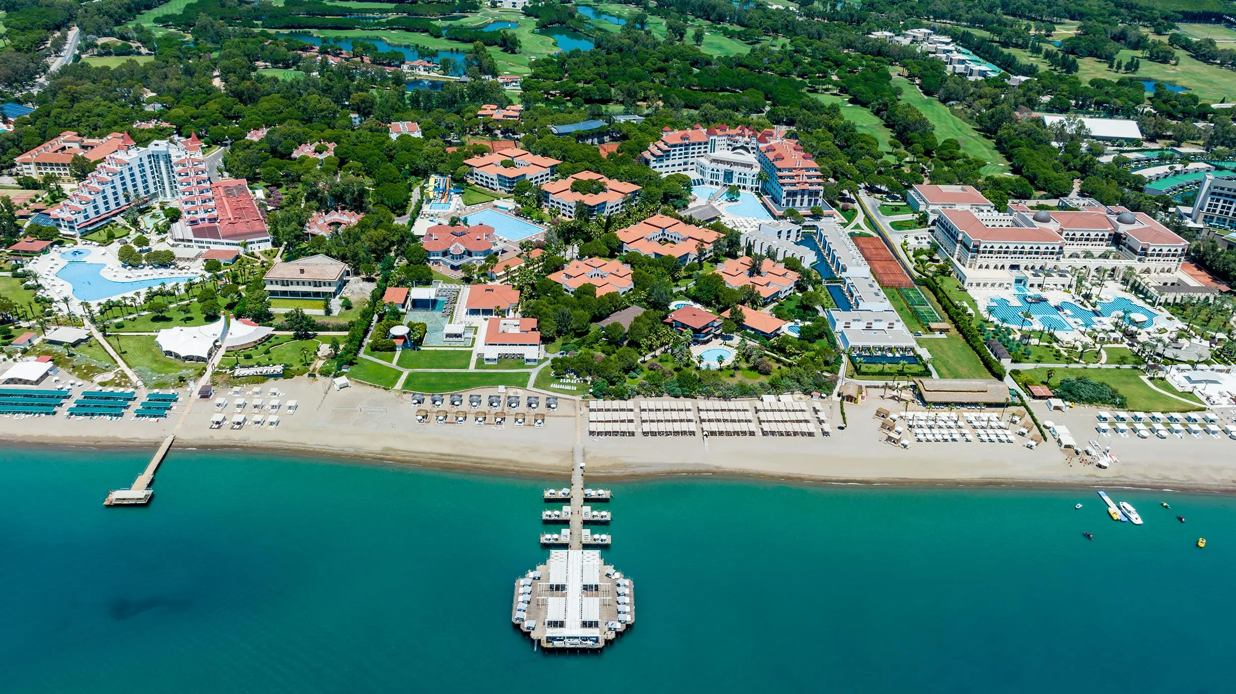 Въздушна панорама на плажа с дървен кей и комплекса сред зеленина – Sirene Belek Hotel, Белек