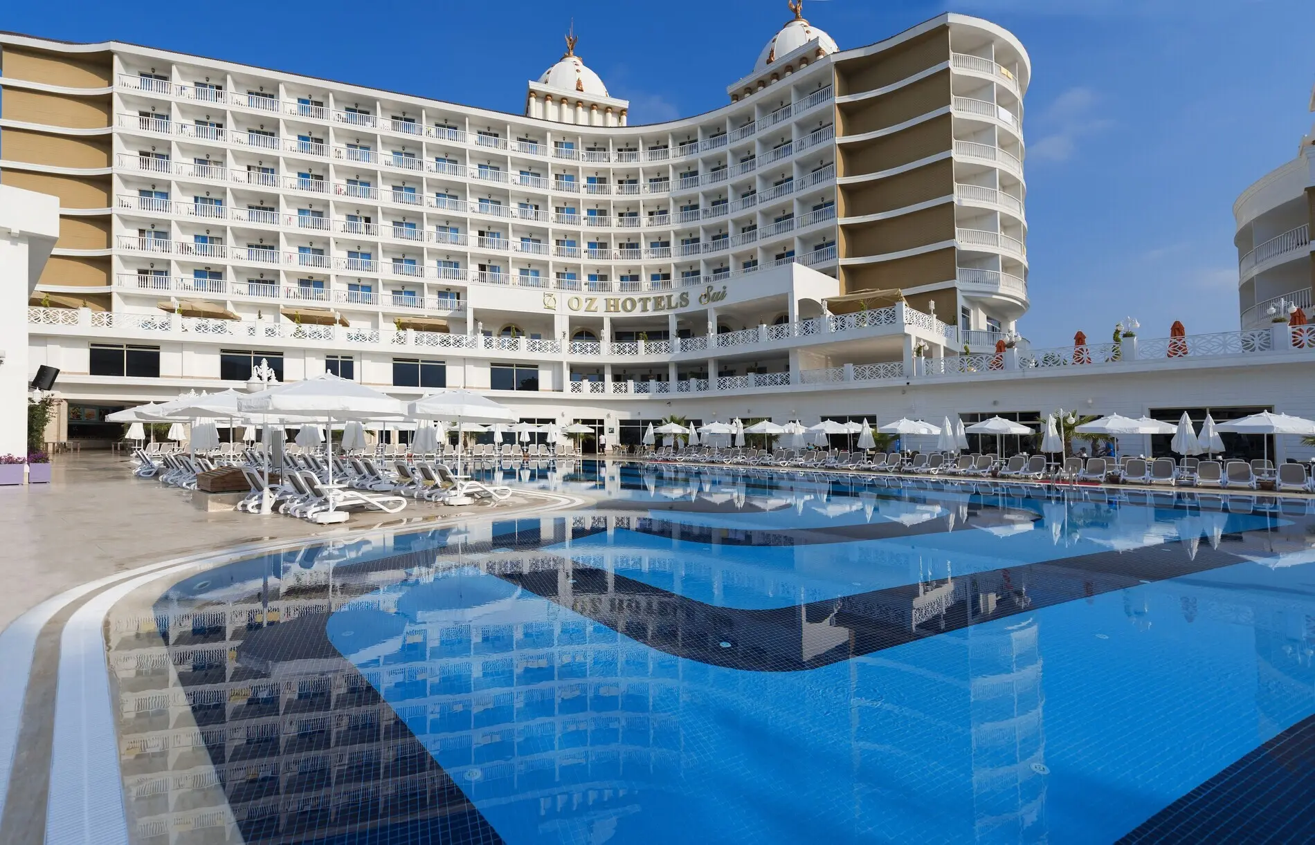 Фасадата на хотела и басейн, в който се отразява сградата – Oz Hotels Sui Resort, Алания
