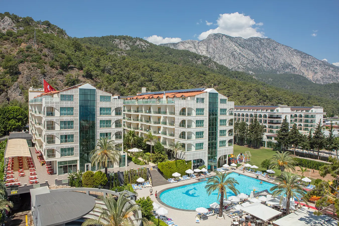 Пететажната сграда и басейнът с палми в подножието на планината Таврос – Grand Ring Hotel, Кемер