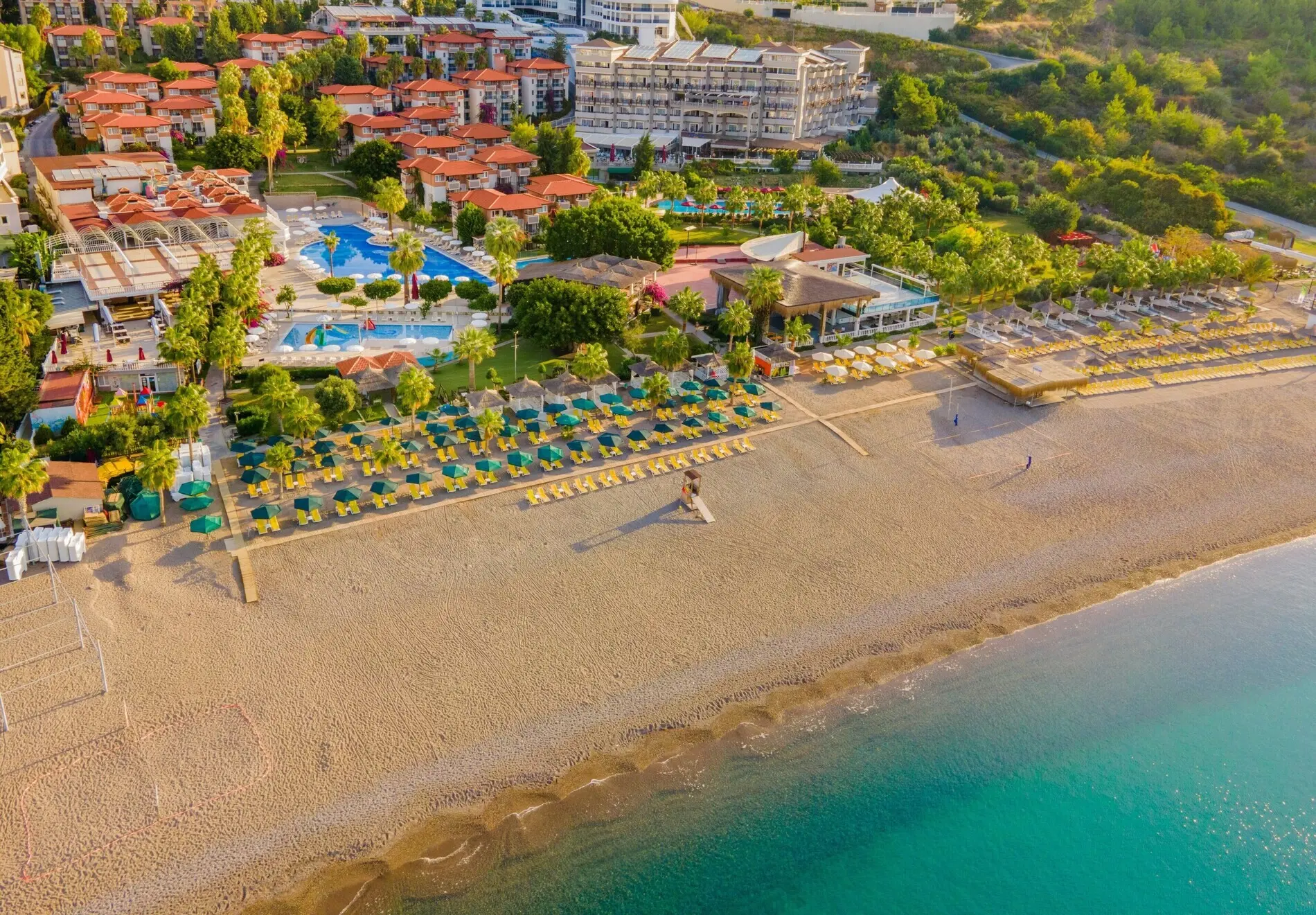 Панорама от въздуха на пясъчния плаж с чадъри и зелената територия на хотела – Justiniano Club Alanya Beach, Алания