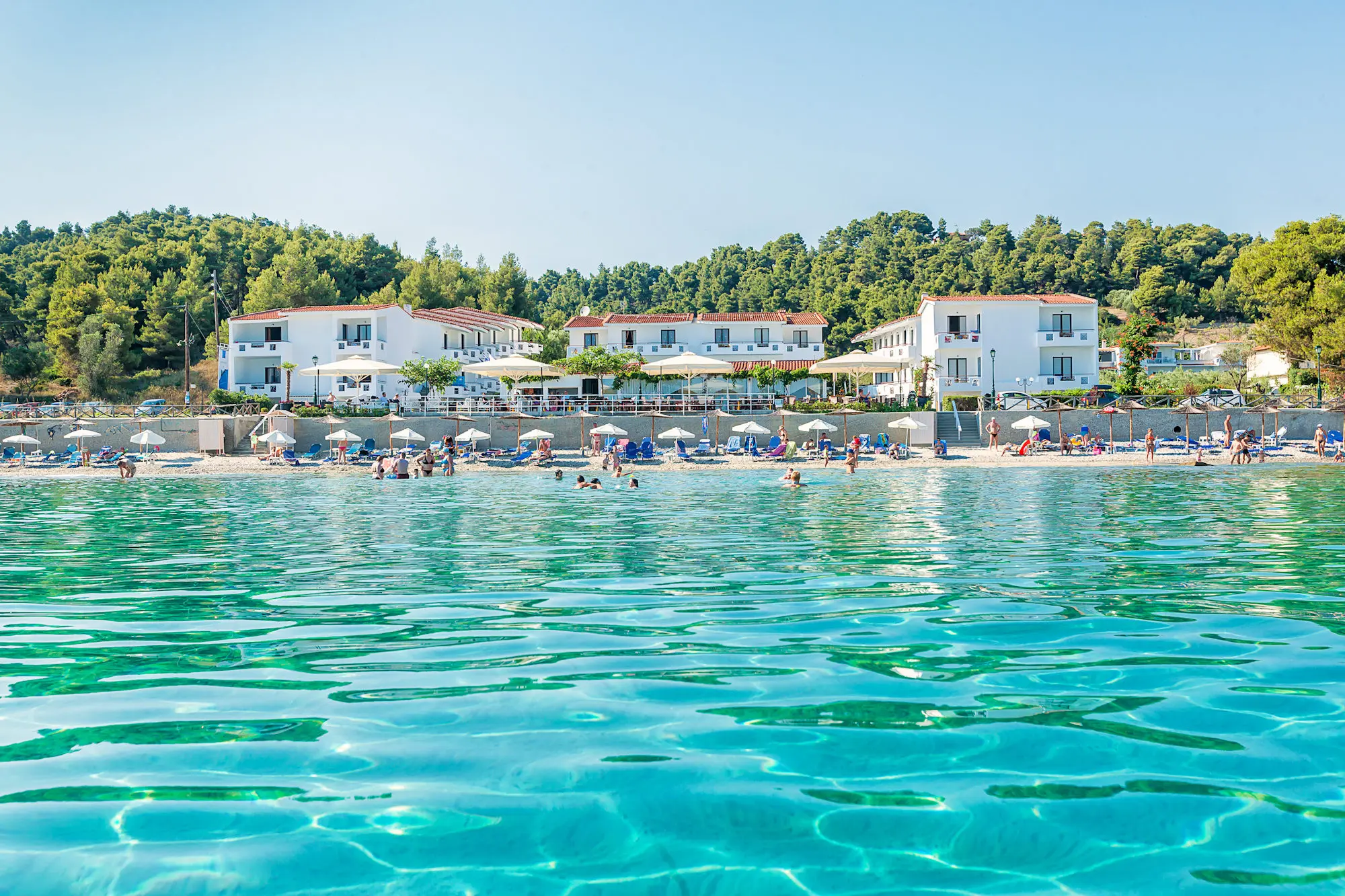 Прозрачно море и плажът пред белите сгради на хотела – Xenios Dolphin Beach, Касандра