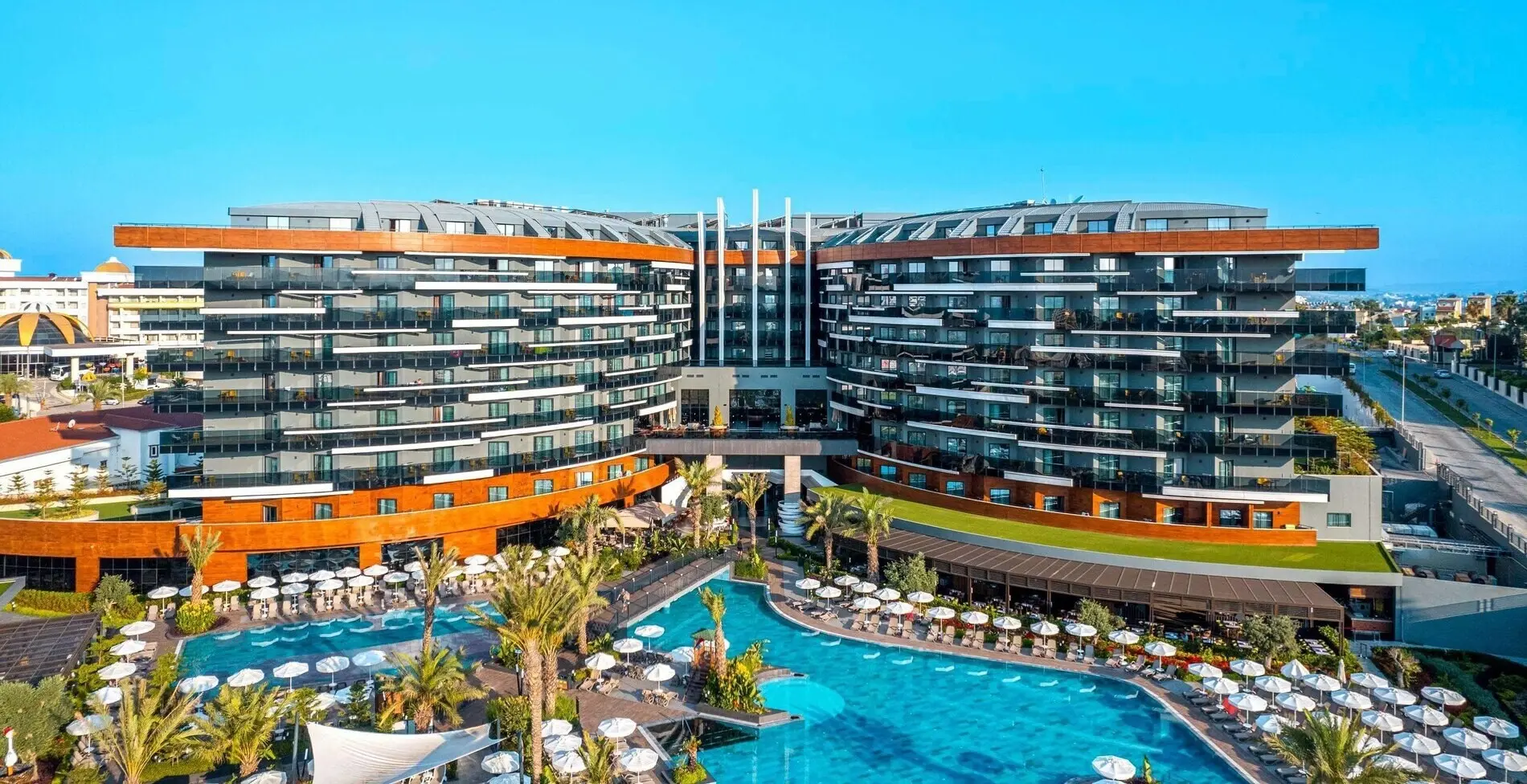 Фасадата на модерния хотел с басейн и чадъри на преден план – Kirman Calyptus Resort & SPA, Сиде