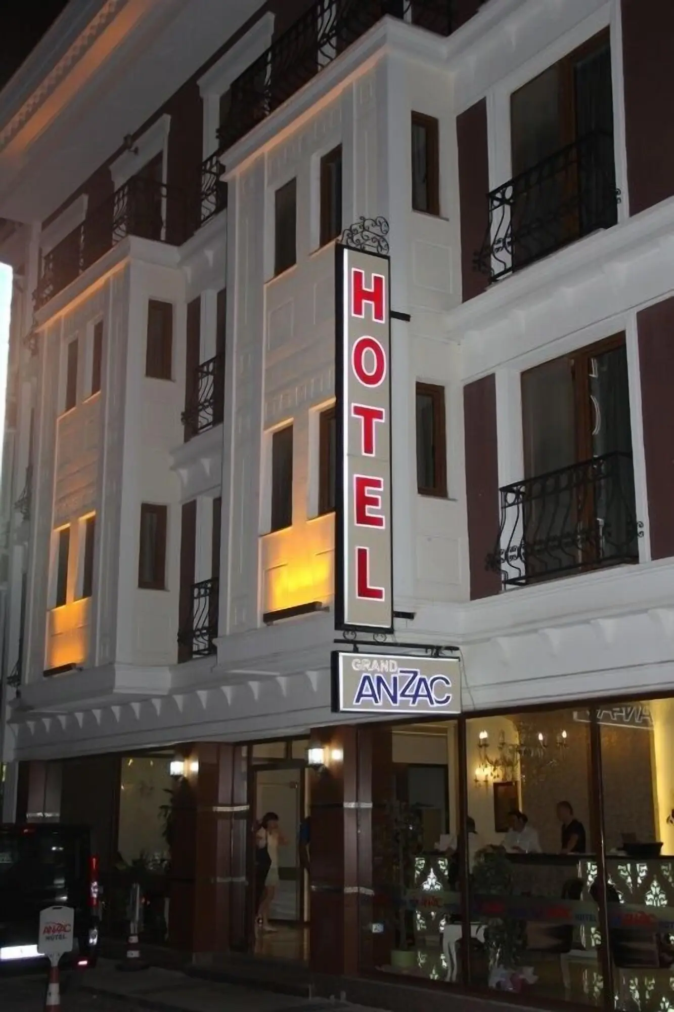 Фасада на хотела с осветен вертикален надпис HOTEL и табела ANZAC – Grand Anzac Hotel, Чанаккале