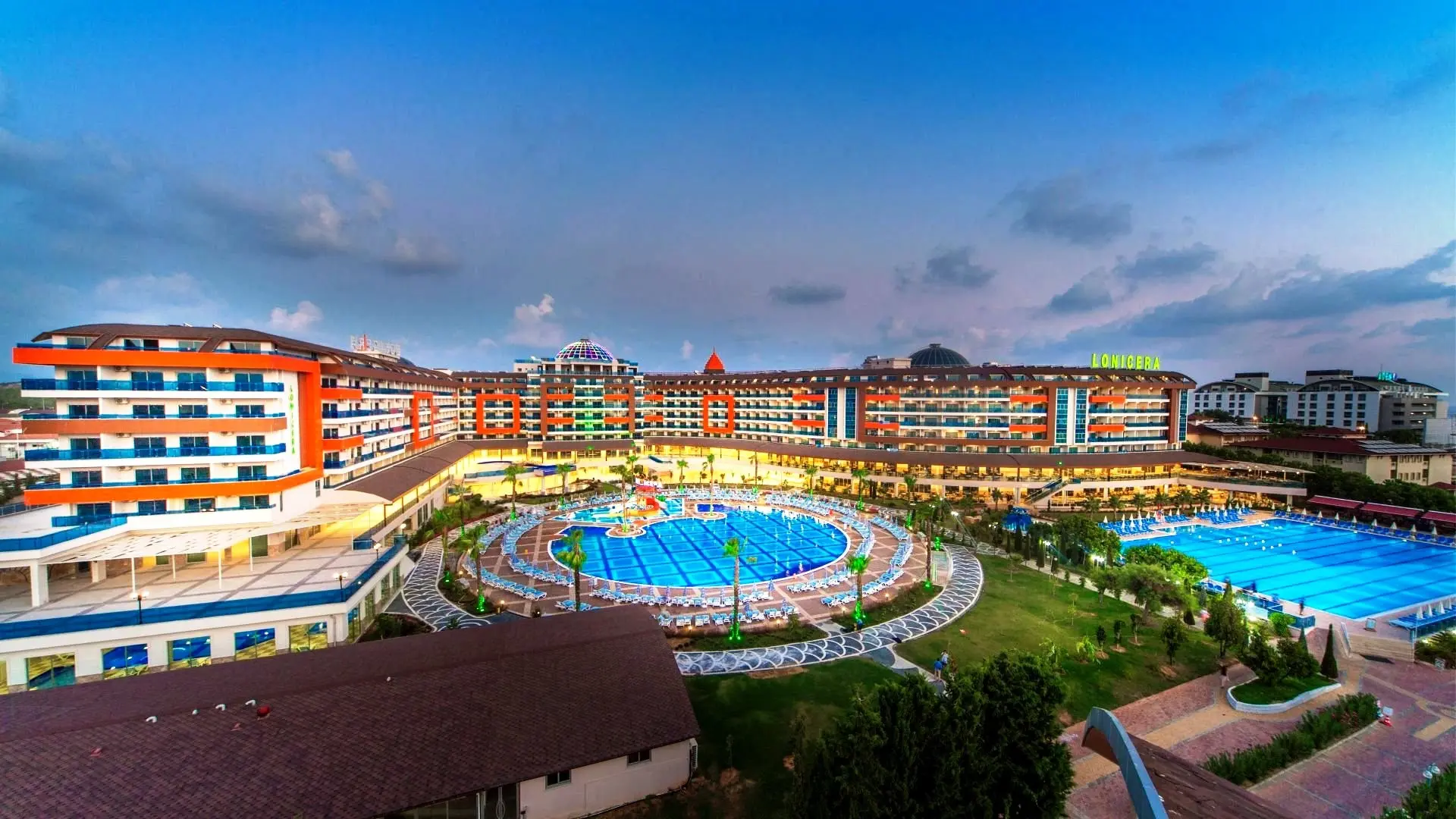 Панорама към хотелските сгради около кръглия басейн по здрач – Lonicera Resort & SPA, Алания
