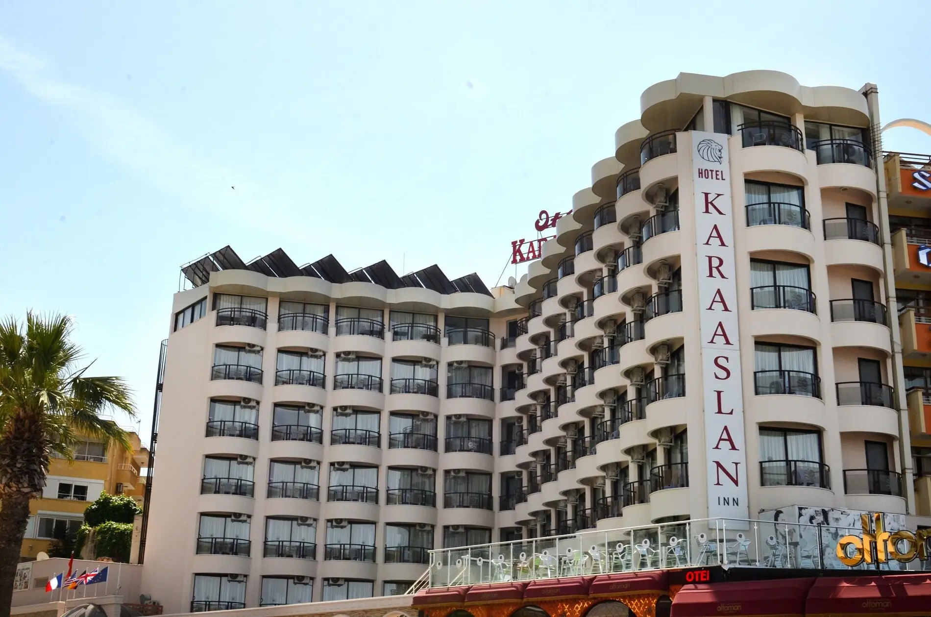 Фасадата на хотела с извити балкони и вертикалния надпис Karaaslan Inn – By Karaaslan Inn Hotel, Кушадасъ