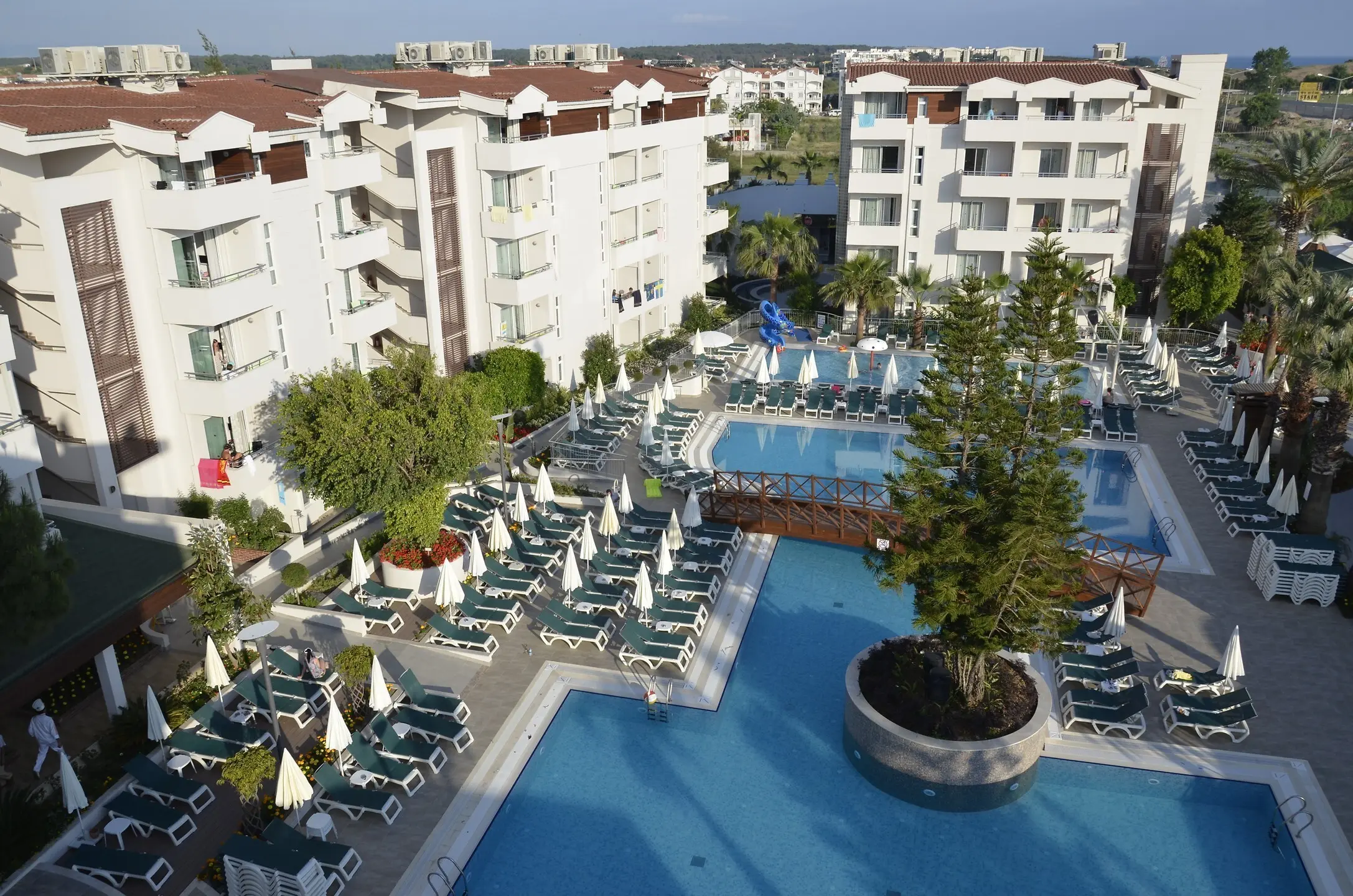 Басейн с шезлонги и палми между белите корпуси на хотела – Side Story Resort & SPA, Сиде