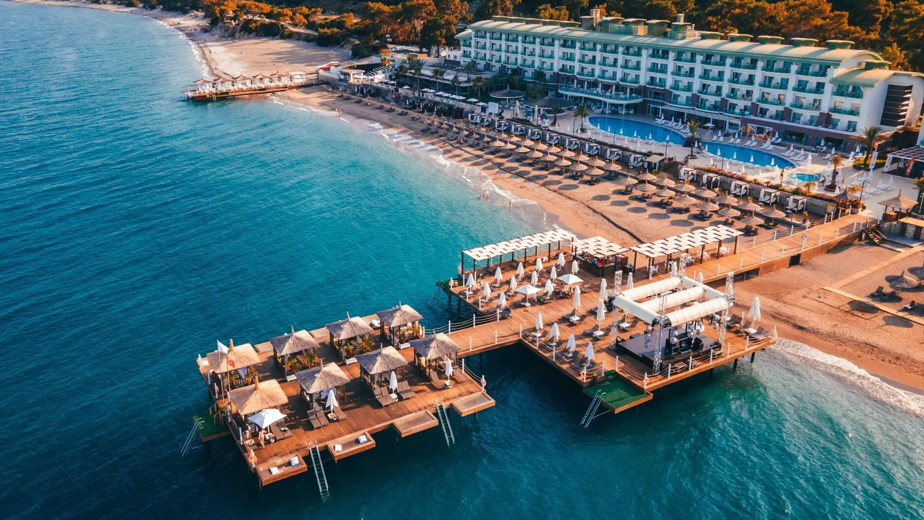 Въздушен изглед към кея с кабани, плажа и тюркоазената вода – Corendon Playa Kemer, Кемер