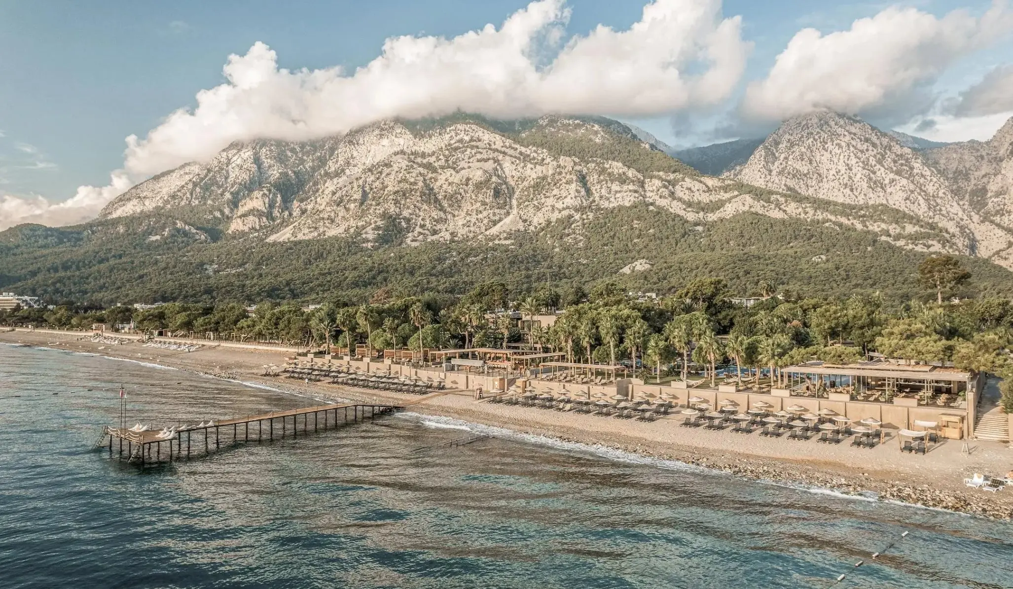 Плажът с кея и шезлонгите в подножието на планината с облаци – Balmy Beach Resort Kemer (18+), Кемер