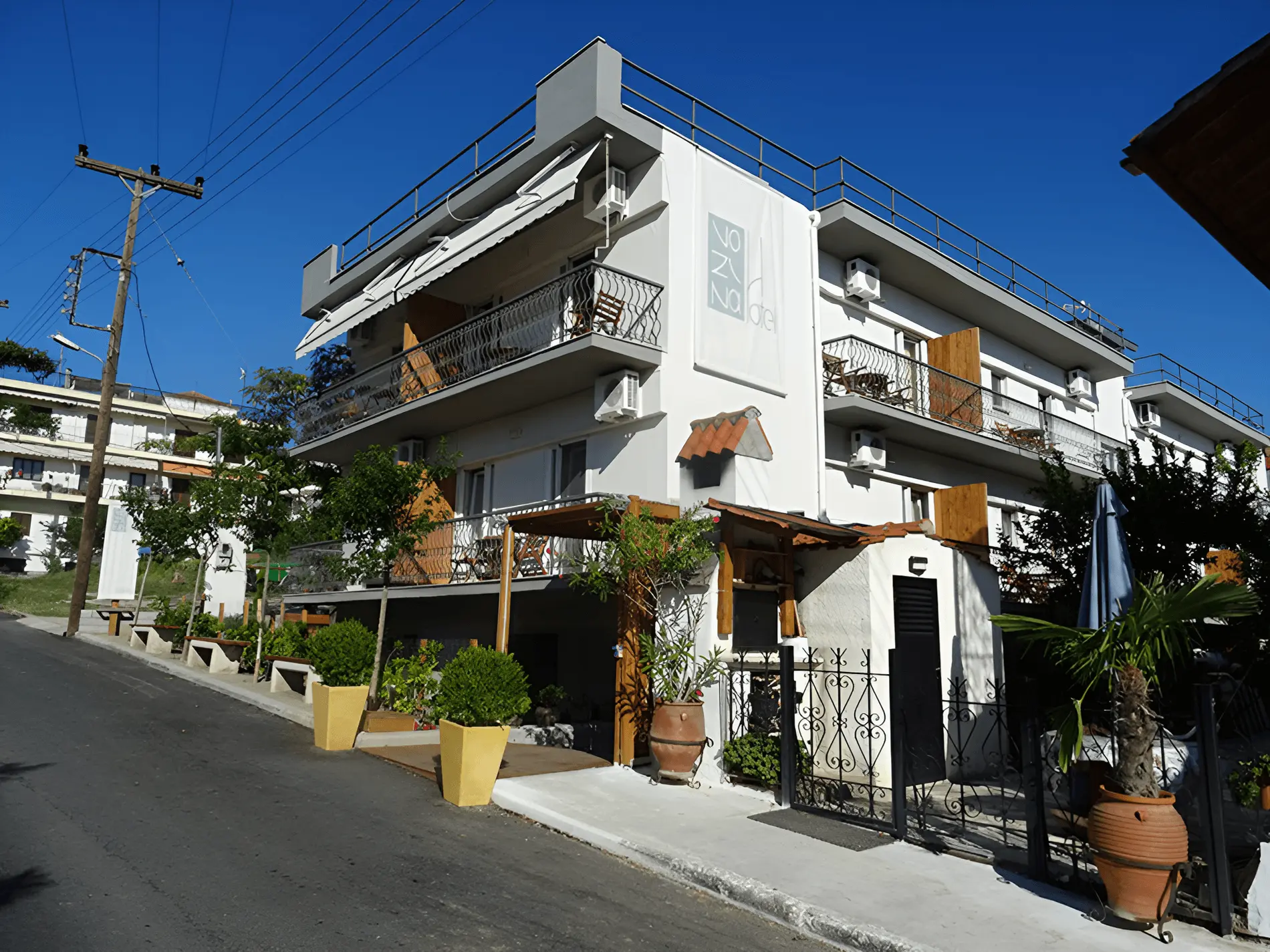 Бялата сграда с балкони и растения в саксии на улицата – Hotel Vozina, Ситония