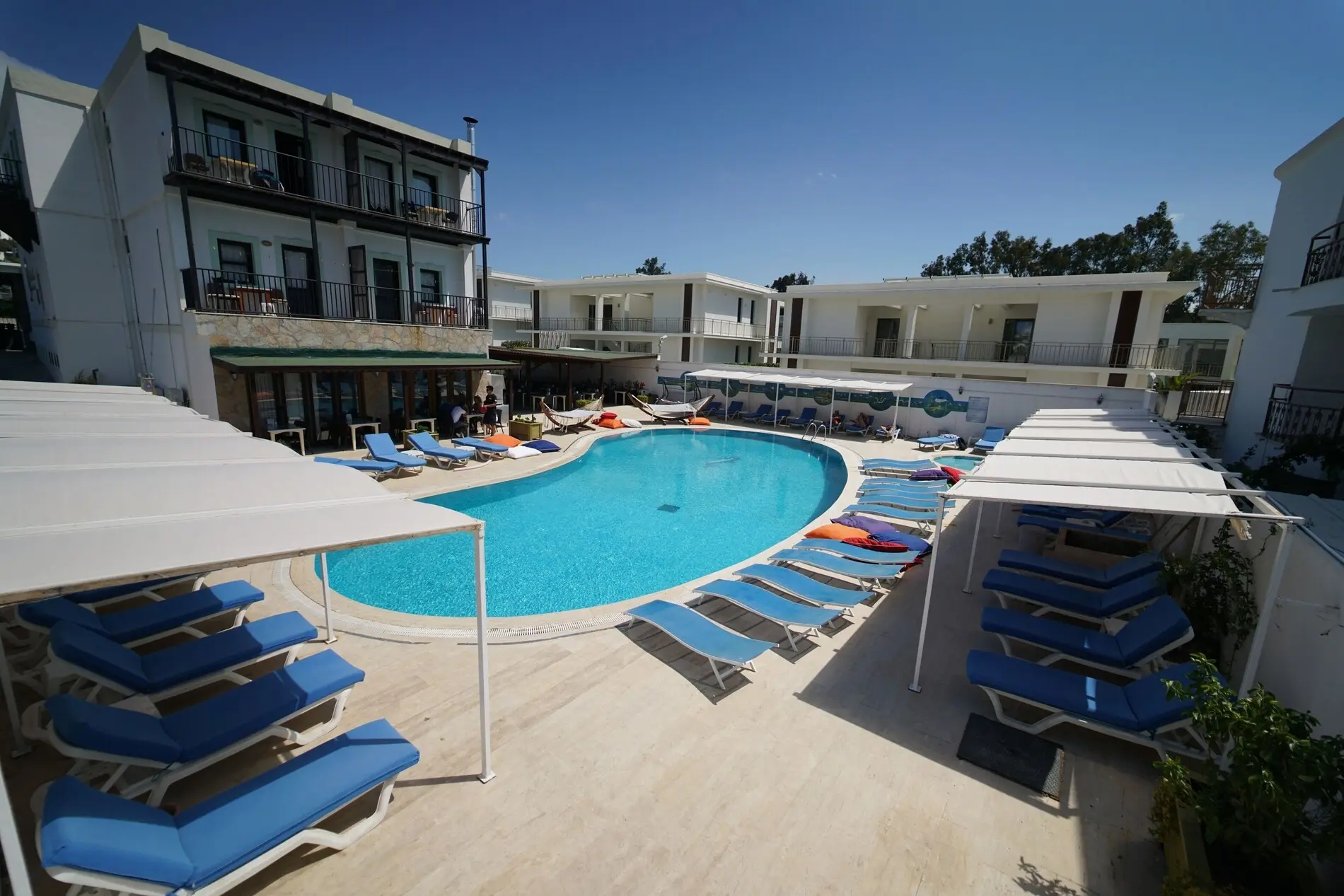 Басейн със сини шезлонги и сенници пред сградите на хотела – Salinas Beach Hotel, Бодрум
