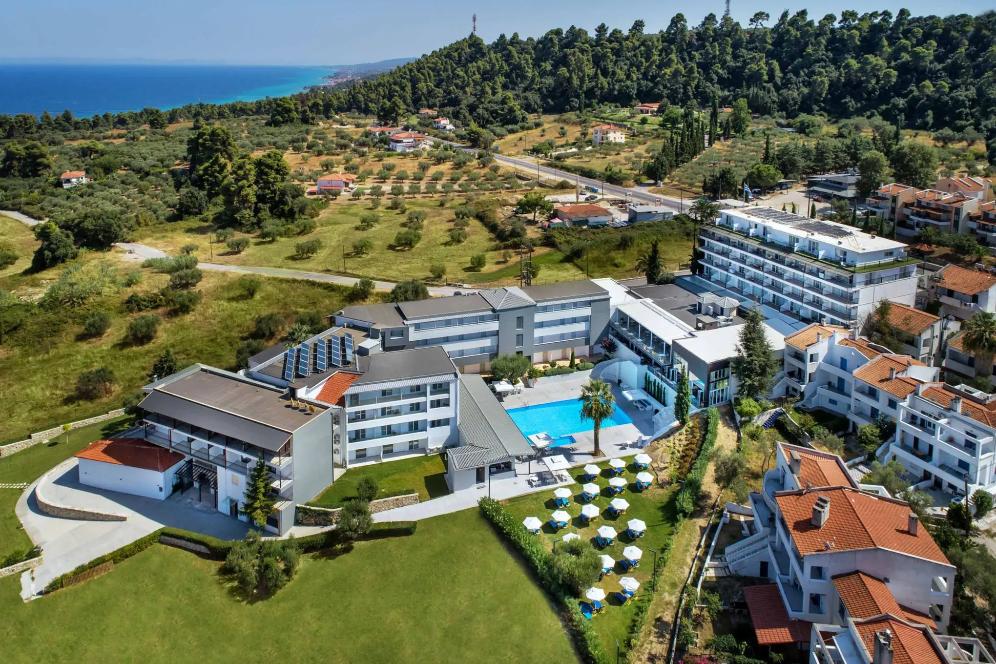 Сградите на хълма, басейнът и морето от въздуха – Kriopigi Hotel, Касандра