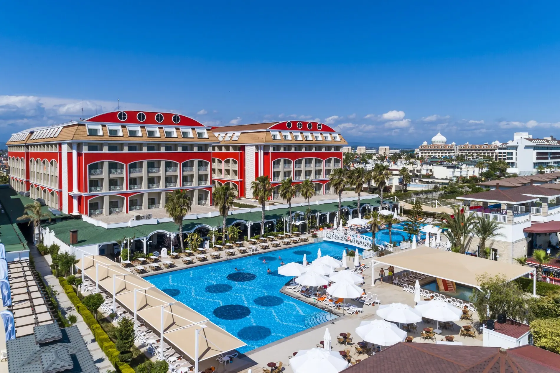 Червената сграда на хотела с басейн и шезлонги пред морето – Orange County Belek, Белек