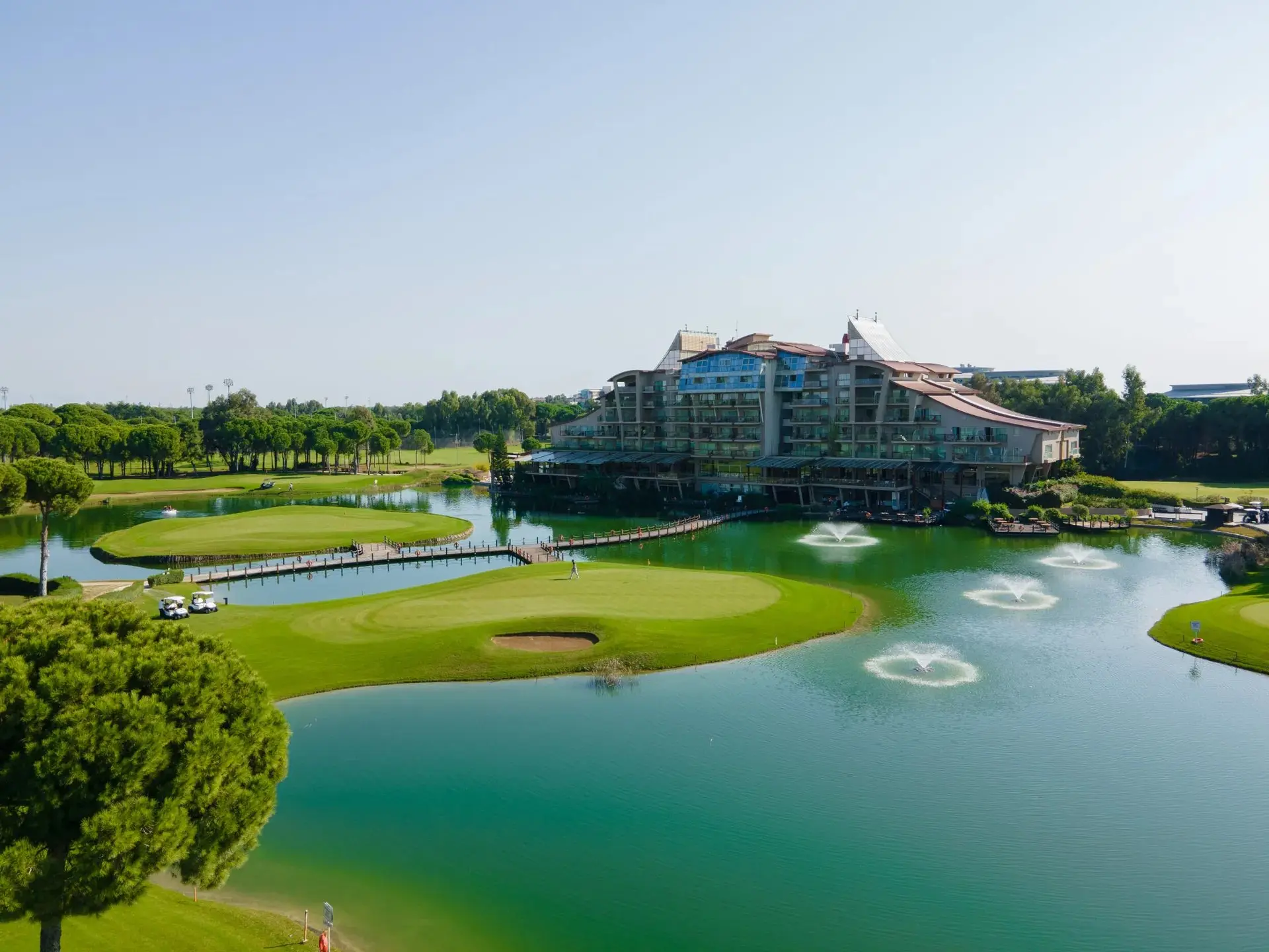 Хотелската сграда отвъд езеро с фонтани и зелените голф игрища – Sueno Hotels Golf Belek, Белек