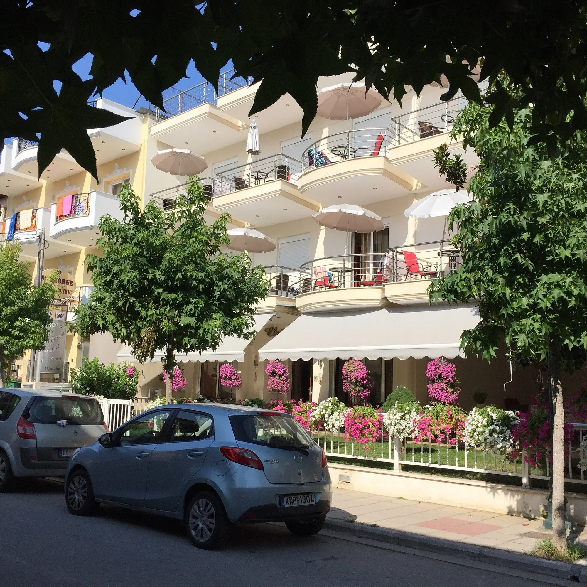 Фасадата на хотела с балкони и цветя на улицата – Christina Hotel, Олимпийска ривиера