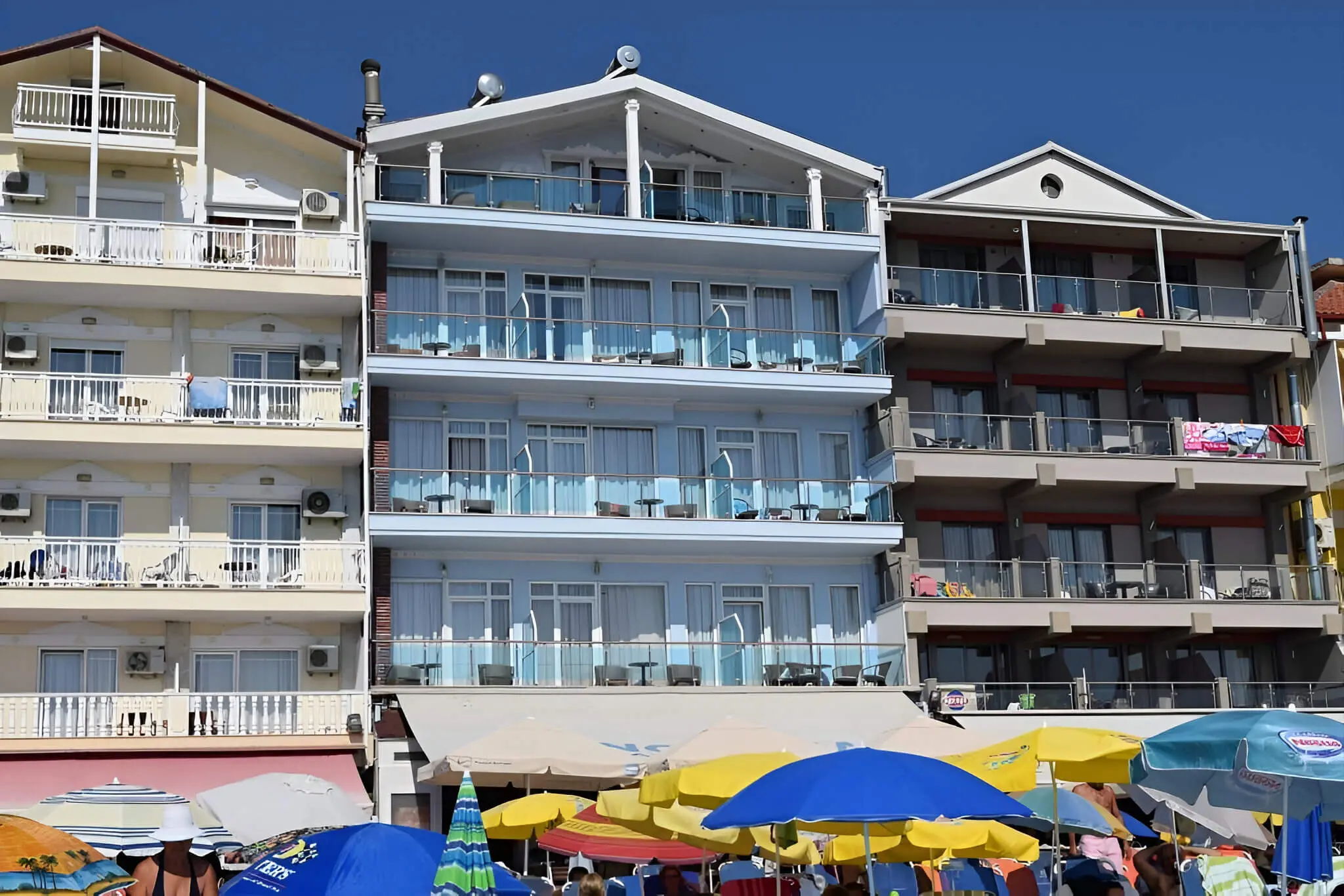 Фасада с балкони и цветни чадъри на плажа пред хотела – Panorama Hotel, Олимпийска ривиера