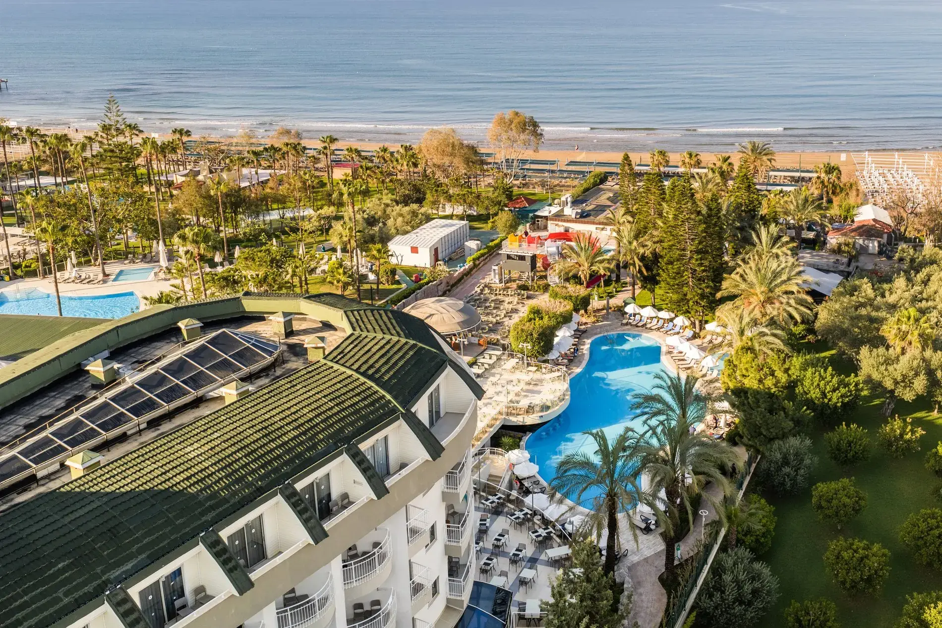 Главната сграда, басейнът и палмовата градина отгоре към брега – Side Sun Hotel, Сиде