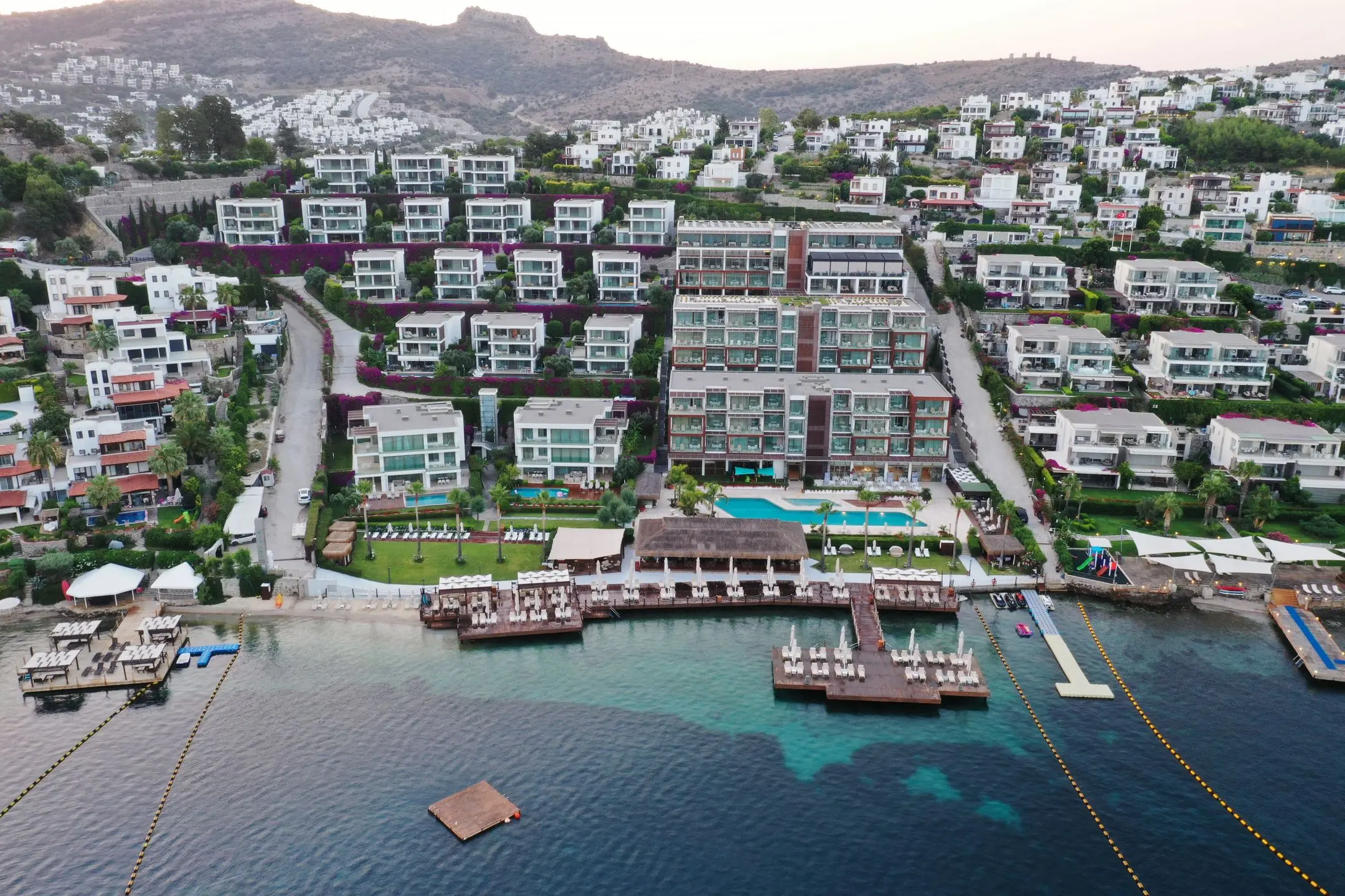 Хотелът на брега на залива Гюндоан с кейове и селото по хълма – Mivara Luxury Bodrum, Бодрум