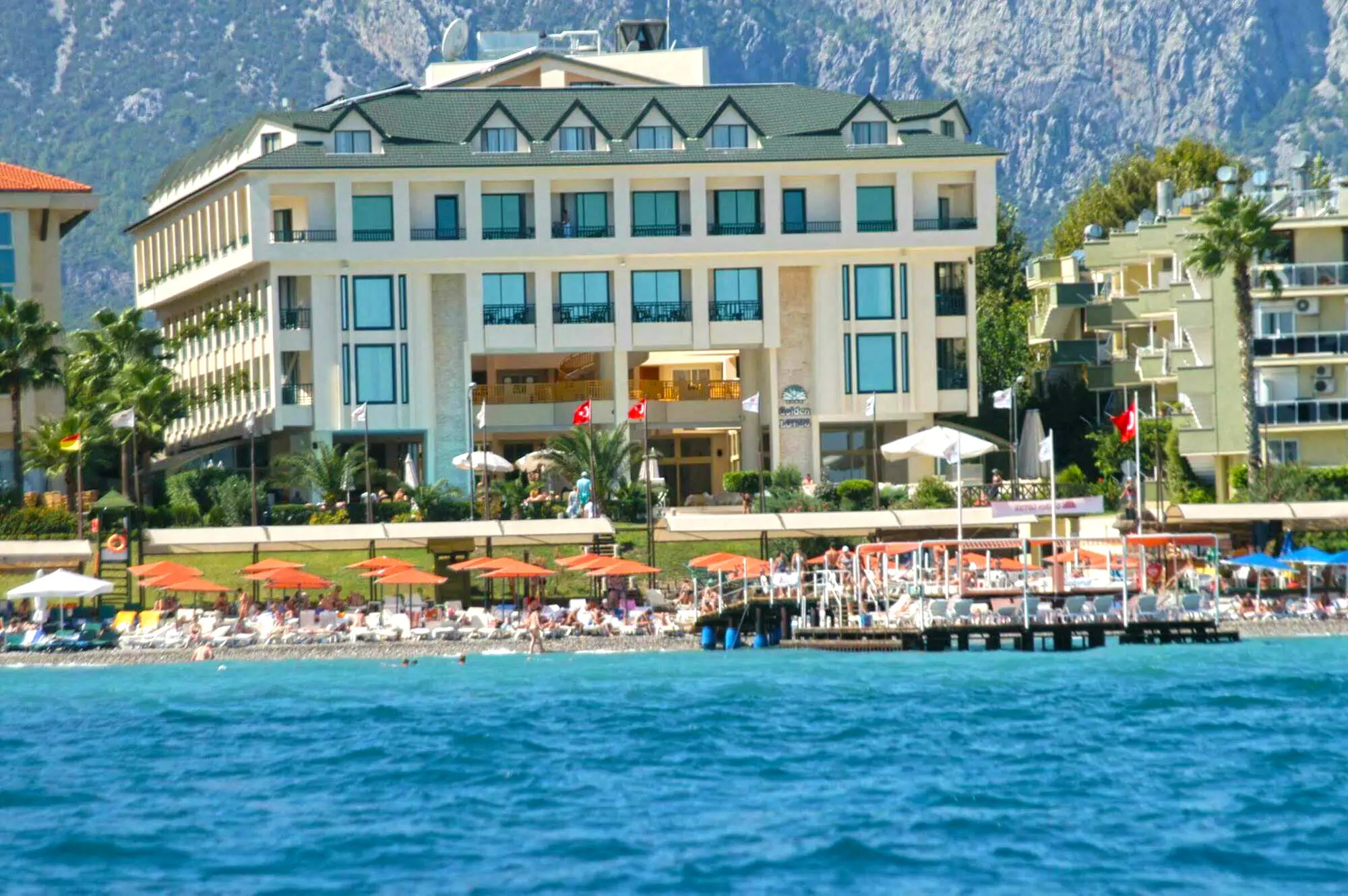 Хотелът, сниман от морето, с плаж и планини зад сградата – Golden Lotus Hotel, Кемер