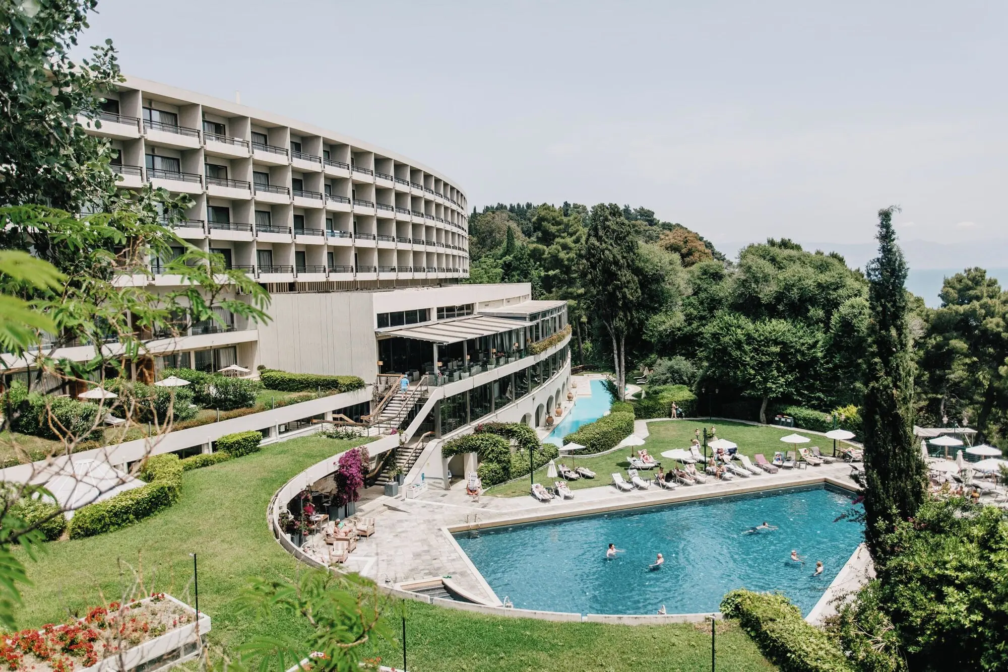 Извитата сграда на хотела над басейна и градината – Corfu Holiday Palace, Корфу