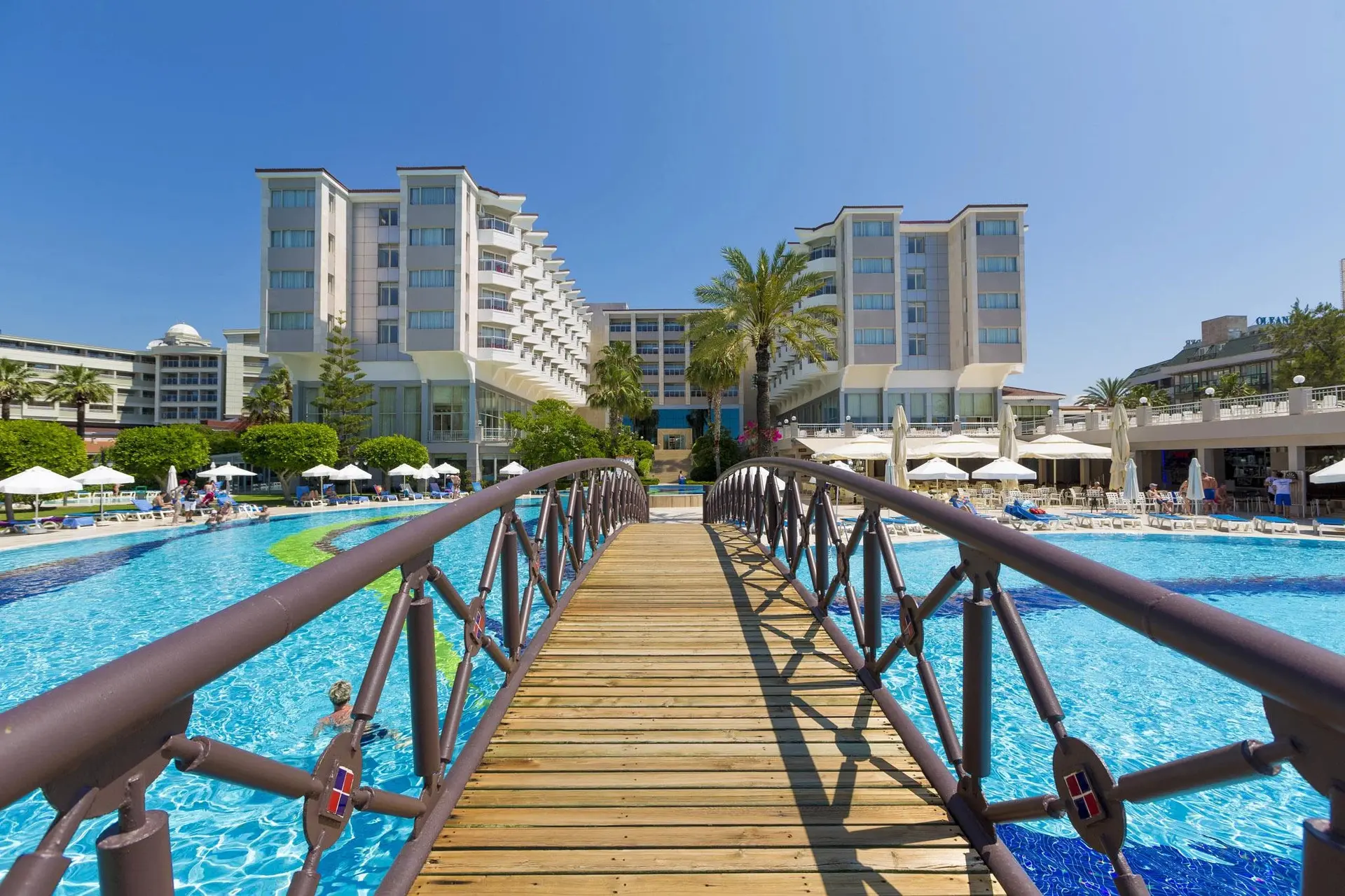 Дървен мост над басейна с изглед към сградите на хотела и палмите – Hotel Terrace Beach Resort, Сиде