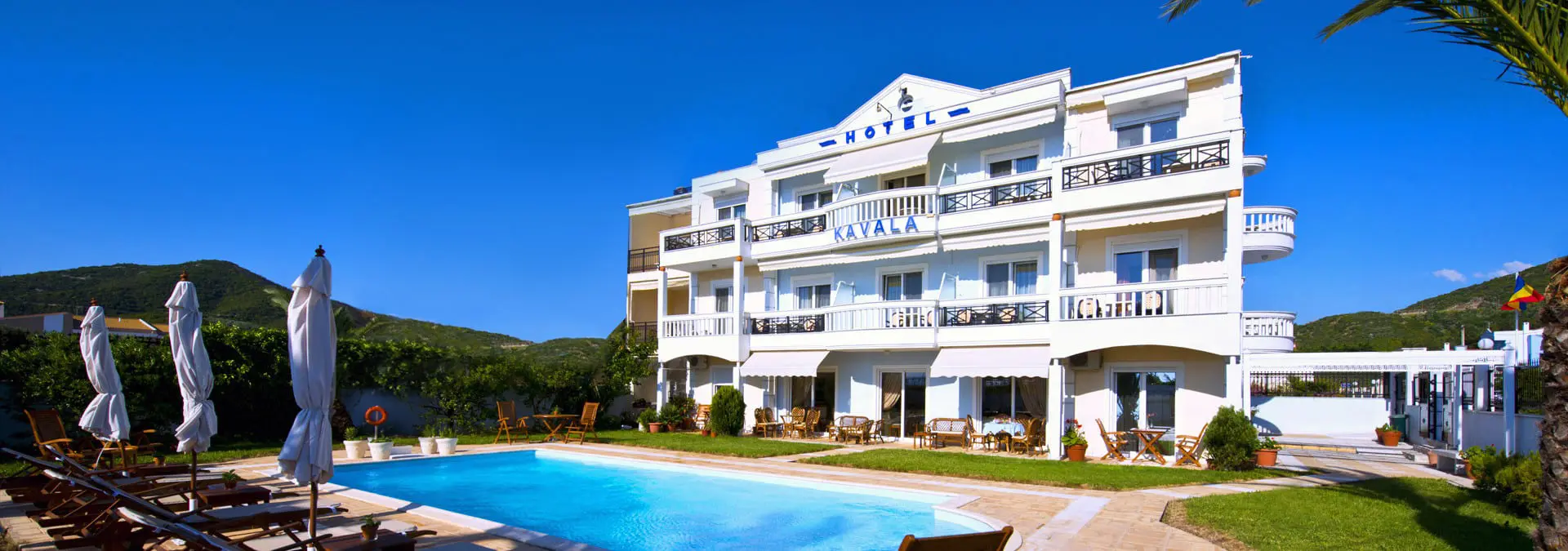Бялата сграда с балкони и басейн отпред – Kavala Beach Hotel Apartments, Кавала