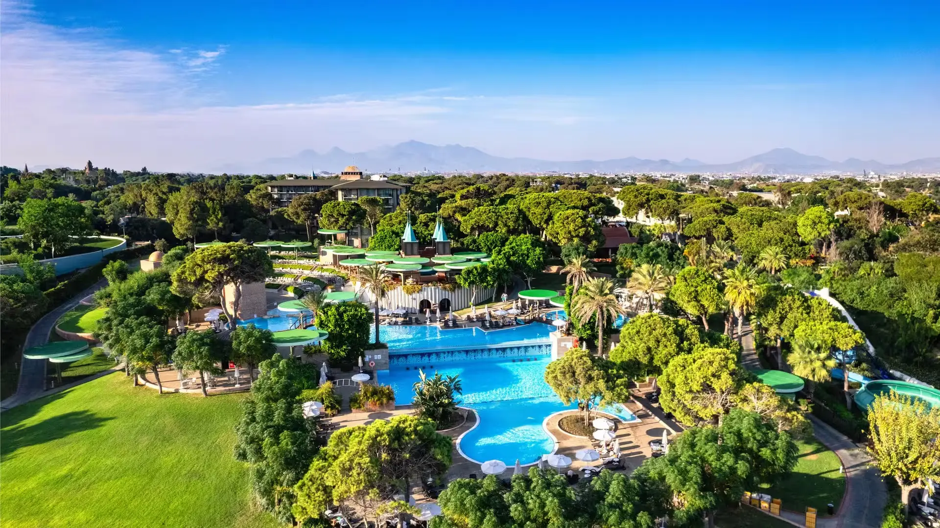 Въздушна гледка към басейни и зелена градина сред борова гора – Gloria Verde Resort, Белек