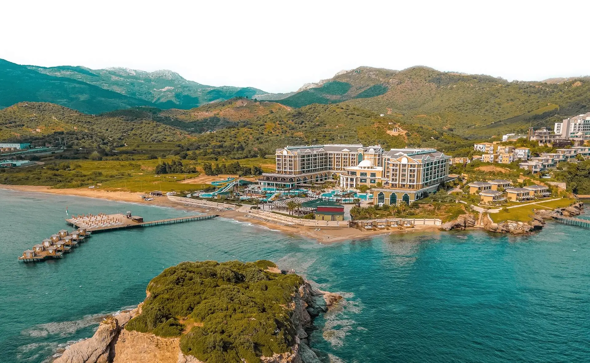 Хотелът на брега с кея и залива сред зелени хълмове отвисоко – Sunis Efes Royal Palace Resort & Spa Hotel, Йоздере