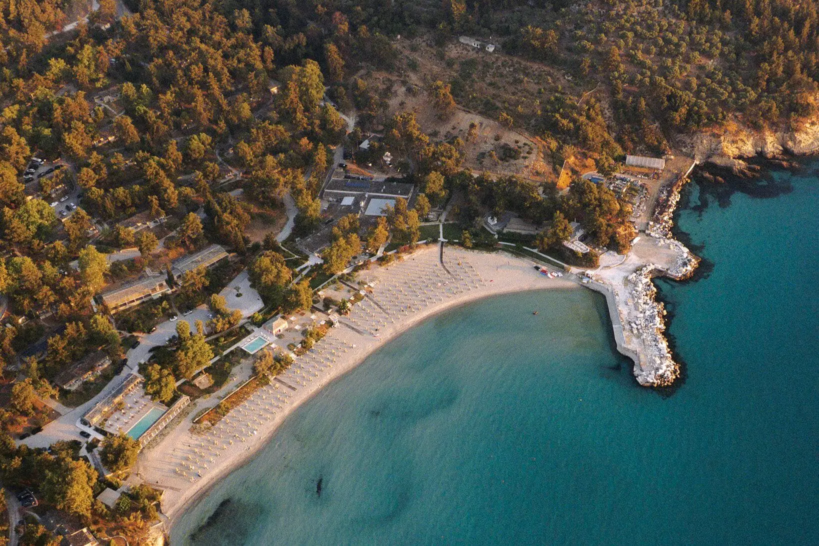 Въздушен изглед към извития плаж и бунгалата сред боровете – Makryammos Bungalows, Тасос