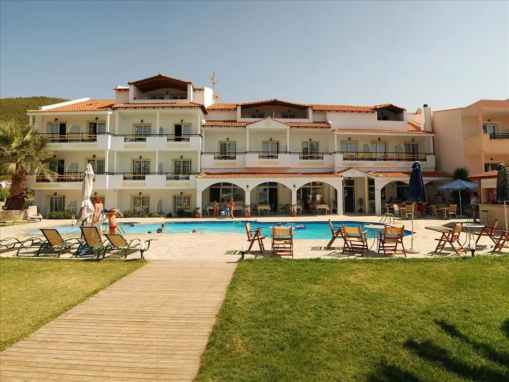 Хотелската сграда с арки и басейна пред зелената морава – Rachoni Bay, Тасос