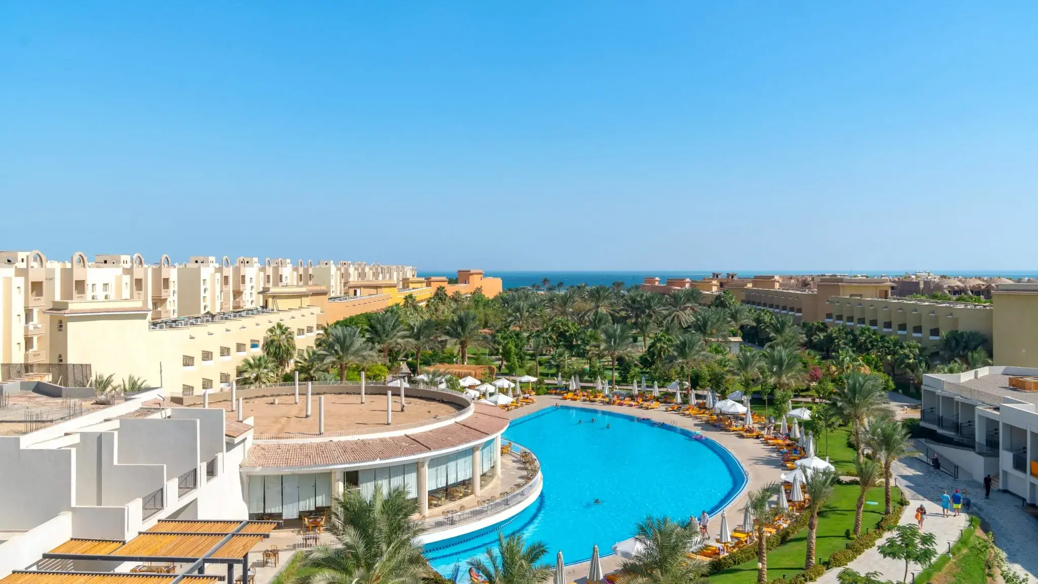 Панорамен изглед към извития басейн сред палмовата градина и морето – Sunny Beach Three Corners Hurghada, Хургада
