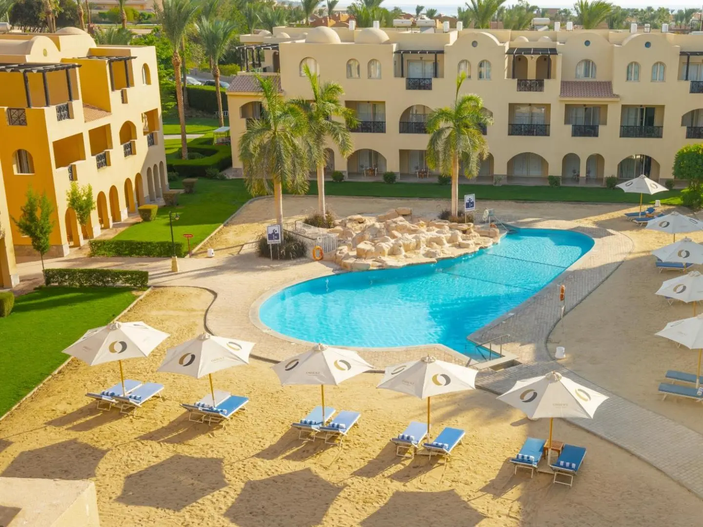 Басейн със слънчобрани и шезлонги пред хотелските корпуси – Stella Gardens Resort & Spa Makadi Bay, Макади Бей