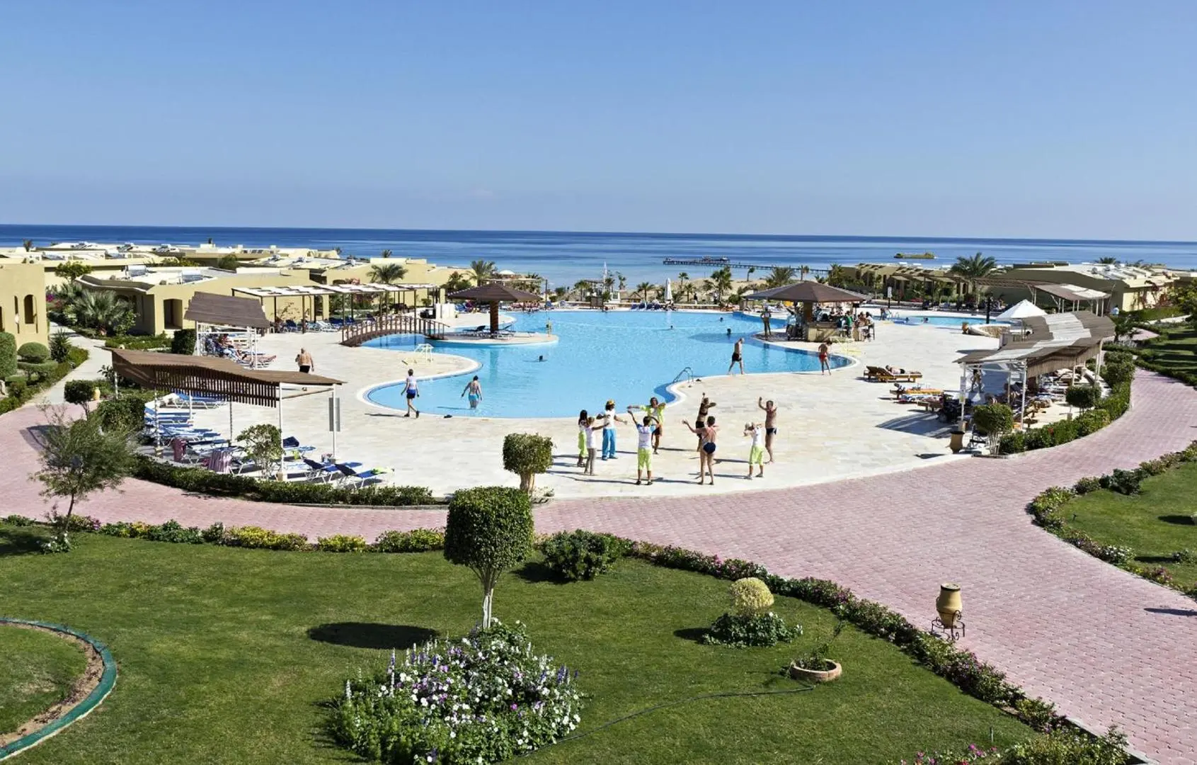 Голям басейн с шезлонги сред зелени морави, морето на фона – Three Corners Fayrouz Plaza Beach Resort, Марса Алам