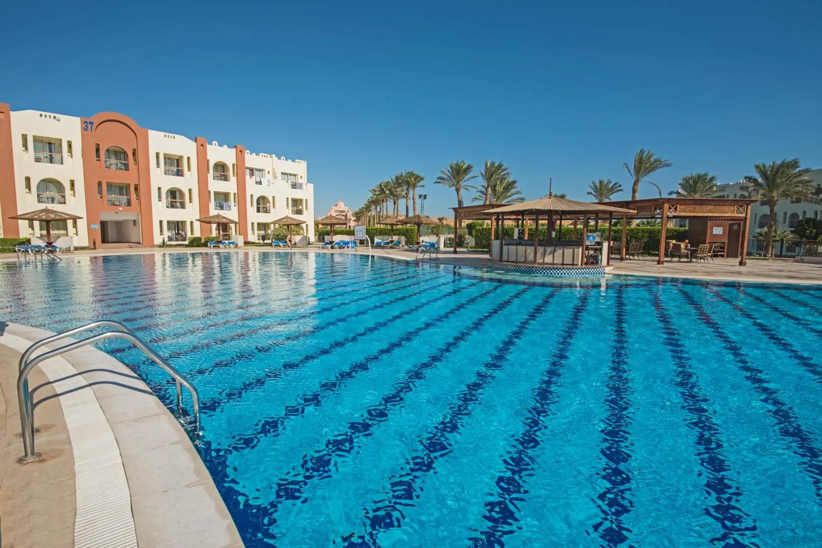 Басейн с коридори за плуване и розови сгради сред палмите – Sunrise Select Royal Makadi Resort, Макади Бей