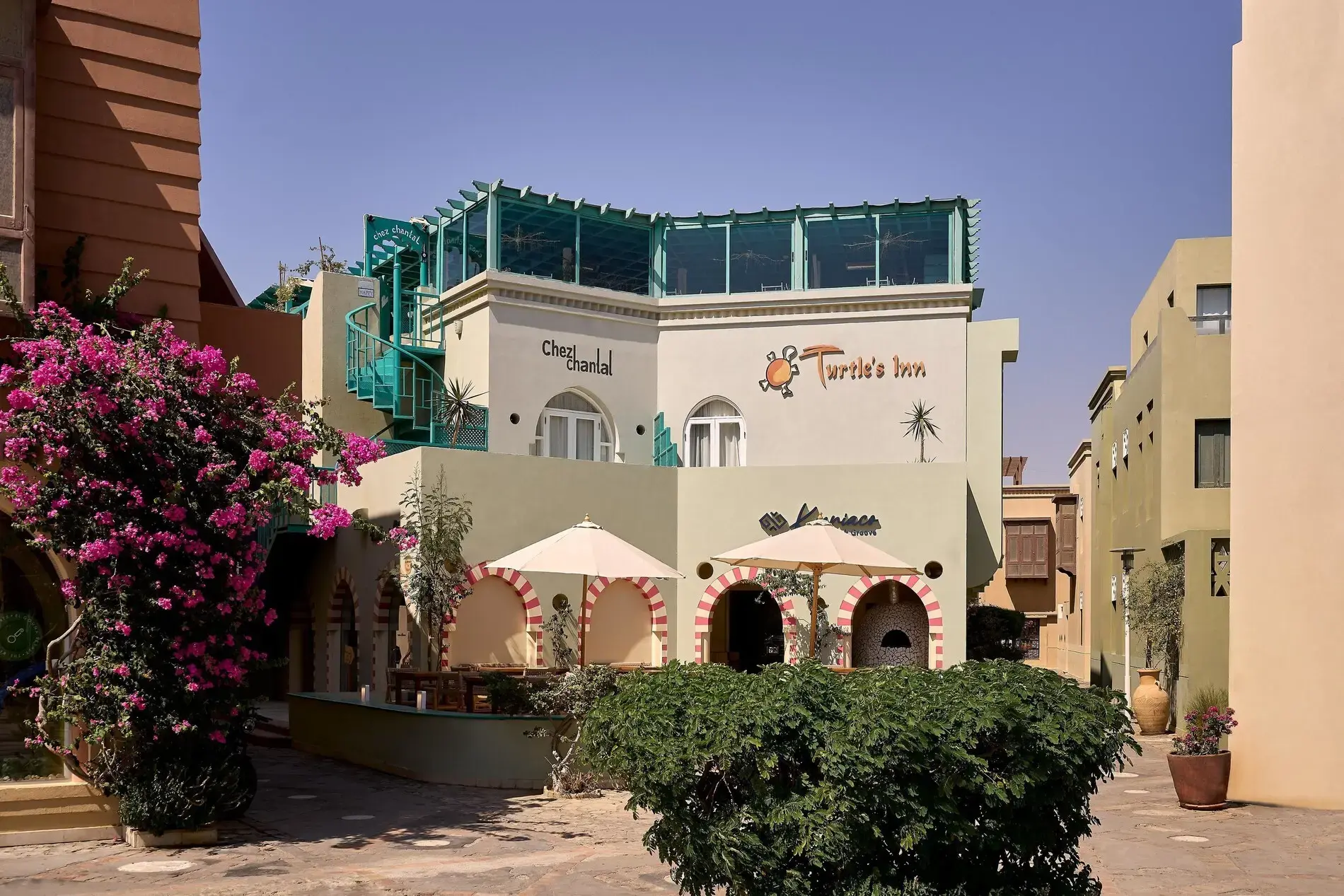 Сградата на хотела с цъфнали бугенвилии и чадър отпред – Turtle's Inn Hotel El Gouna, Ел Гуна