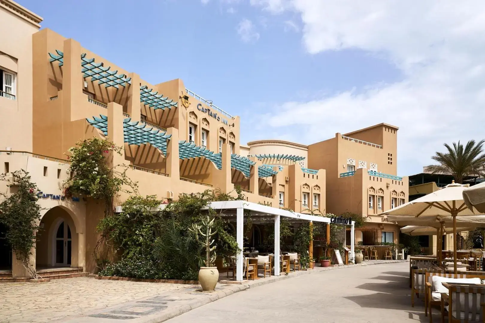 Сградите на хотела с тенти и кафене на открито на улицата към марината – Captain's Inn El Gouna, Ел Гуна