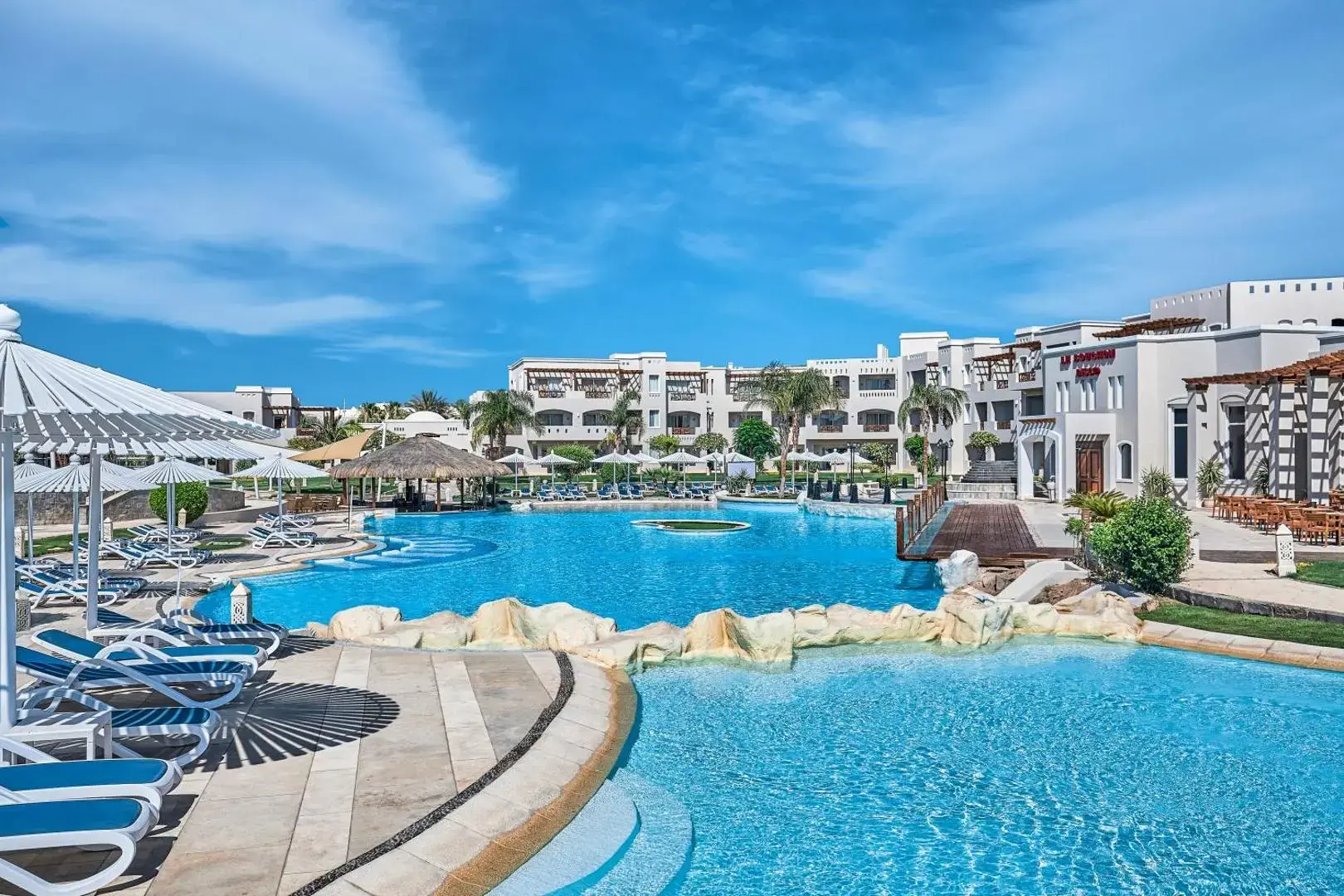Басейн с извита форма и скали сред белите сгради – JAZ Elite Casa Del Mar Beach, Хургада
