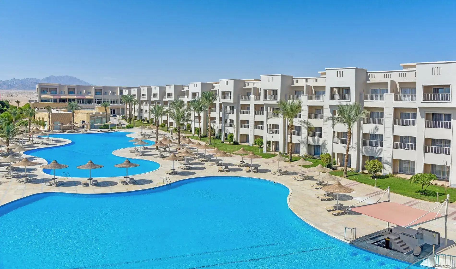 Голям басейн с шезлонги и чадъри покрай белите сгради – JAZ Soma Beach, Сома Бей