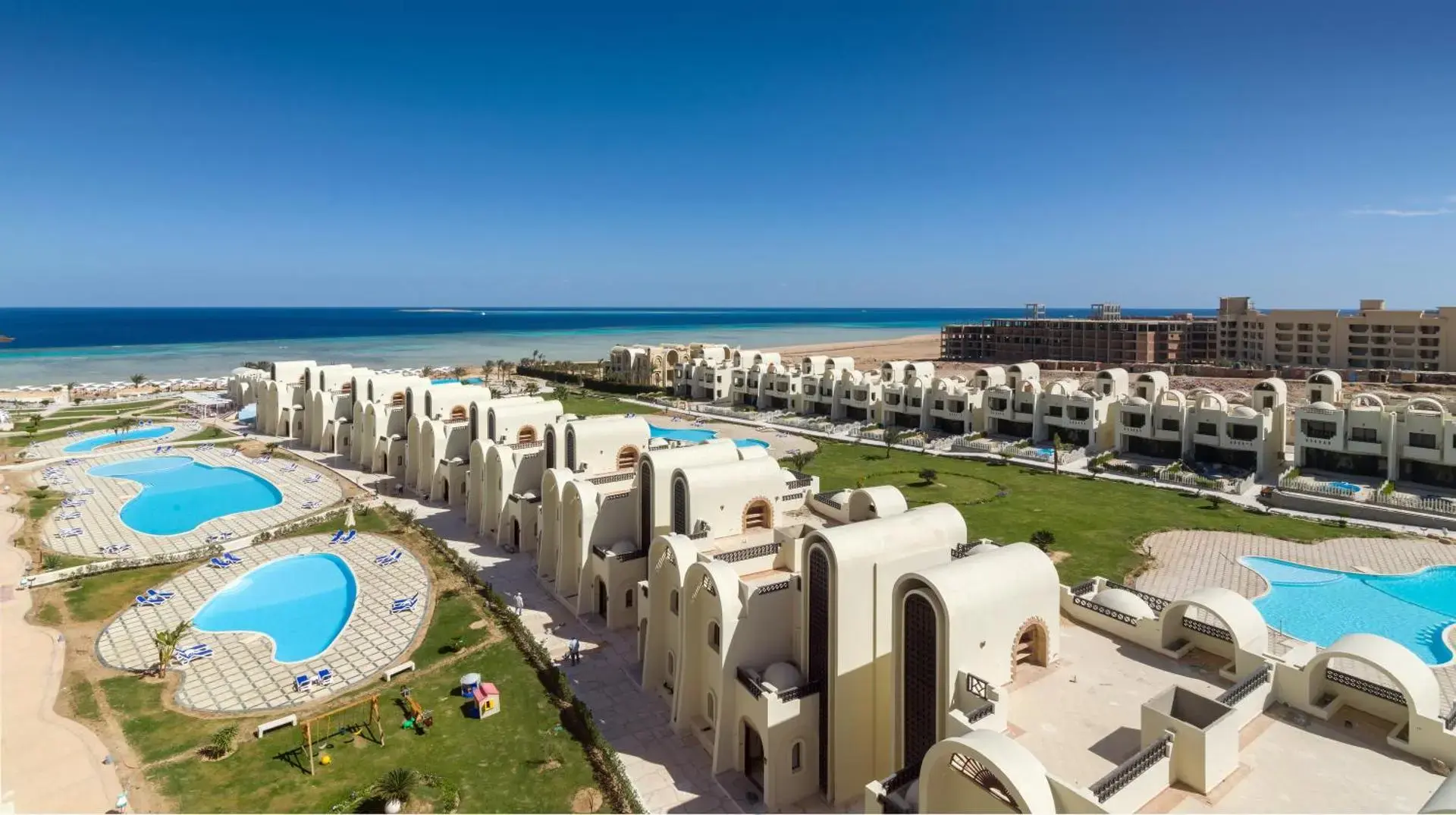 Бели сгради с арки около сини басейни и морето на хоризонта – Gravity Hotel & Aqua Park Sahl Hasheesh, Сал Хашиш