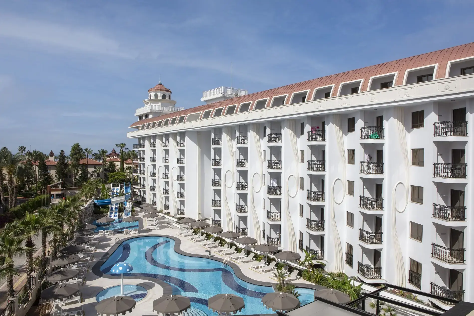 Бял корпус на хотела с балкони и басейн с лагуна сред палми – Blue Marlin Deluxe Spa & Resort, Алания