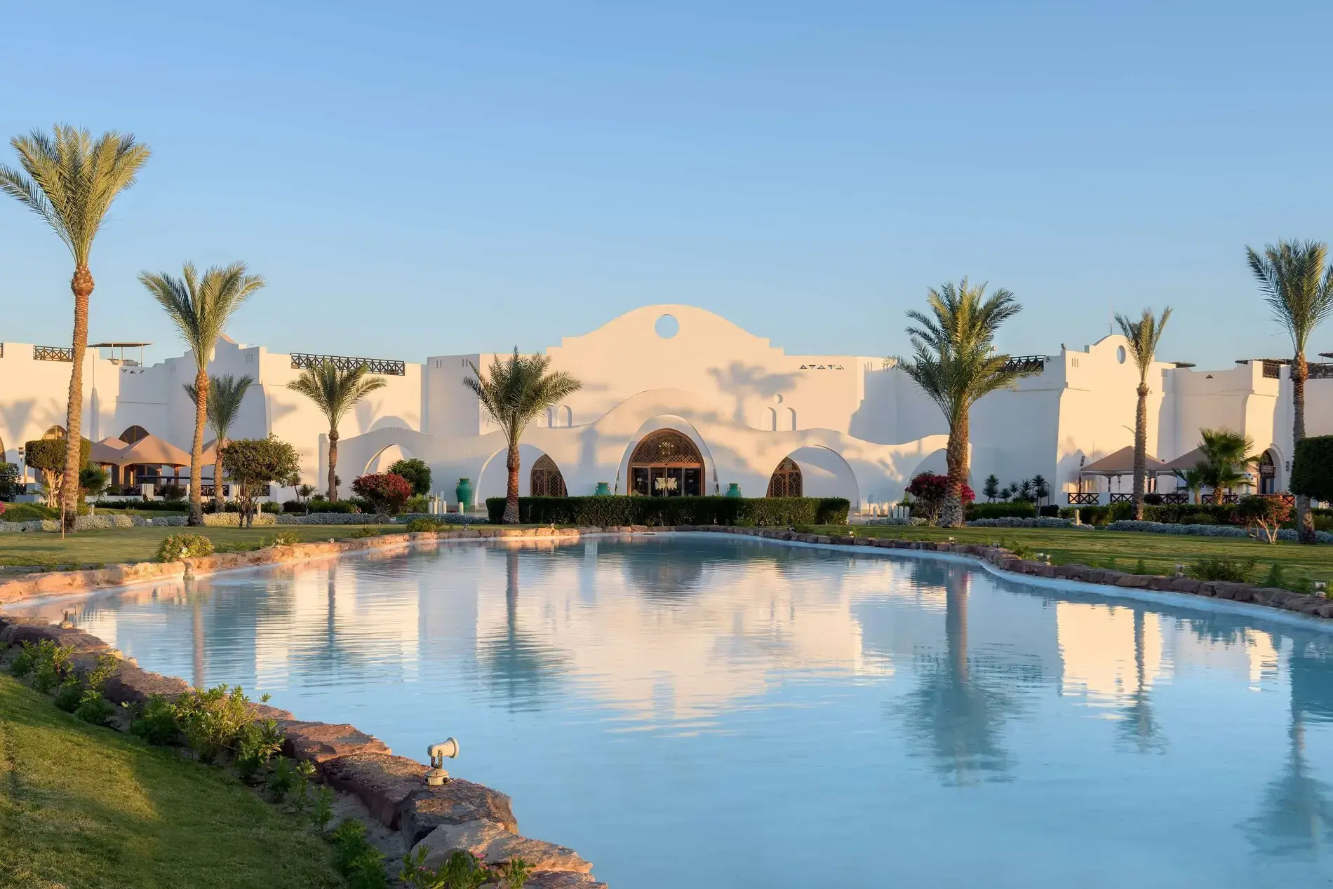 Басейн с отражение на белите сгради в нубийски стил и палми – Hilton Marsa Alam Nubian Resort, Марса Алам