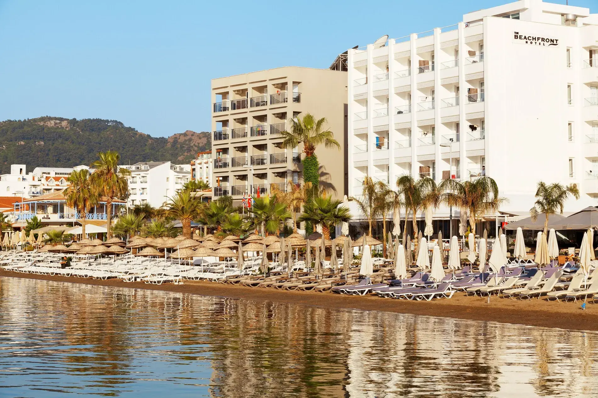 Бялата сграда на хотела с палми, гледана откъм морето – The Beachfront Hotel (16+), Мармарис