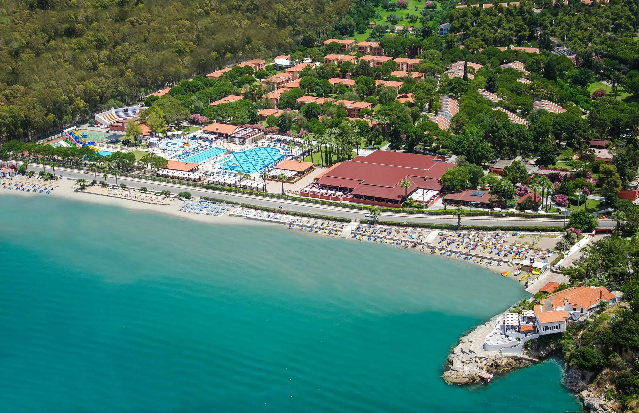 Въздушен изглед към залива, плажа и комплекса сред боровата гора – Kustur Club Holiday Village, Кушадасъ