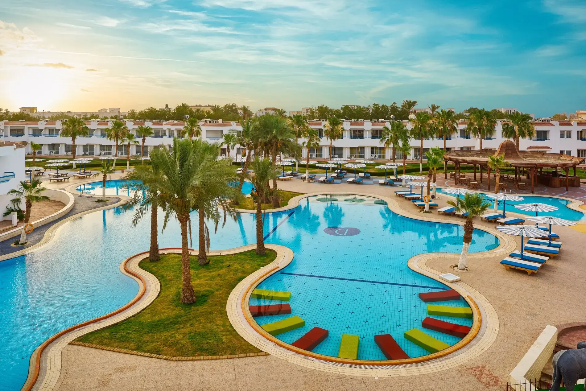 Лагуновидни басейни с палми и шезлонги на изгрев – Dreams Vacation Resort, Шарм Ел Шейх