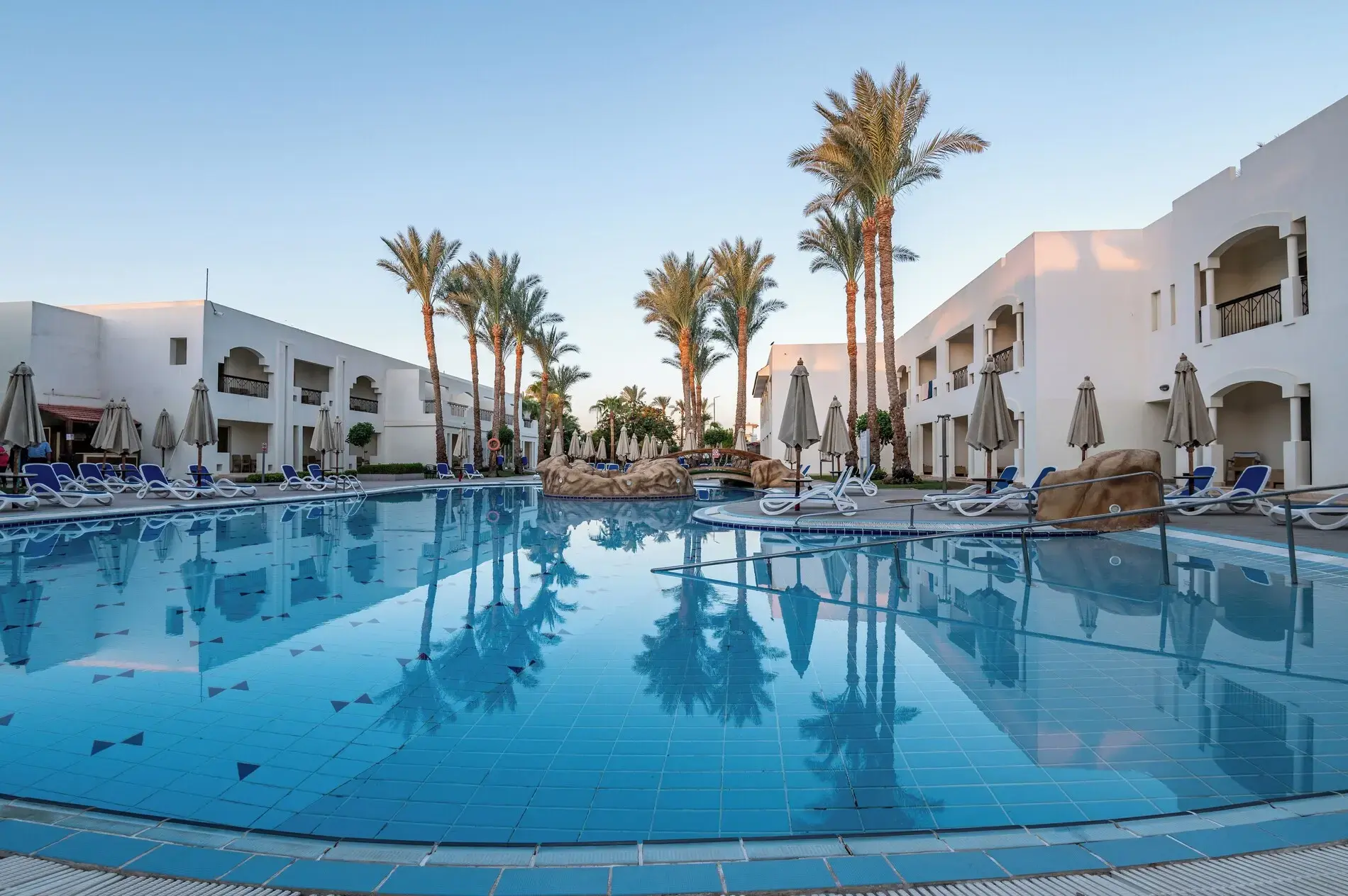 Открит басейн с палми и бели двуетажни сгради през деня – Xperience St. George Homestay, Шарм Ел Шейх