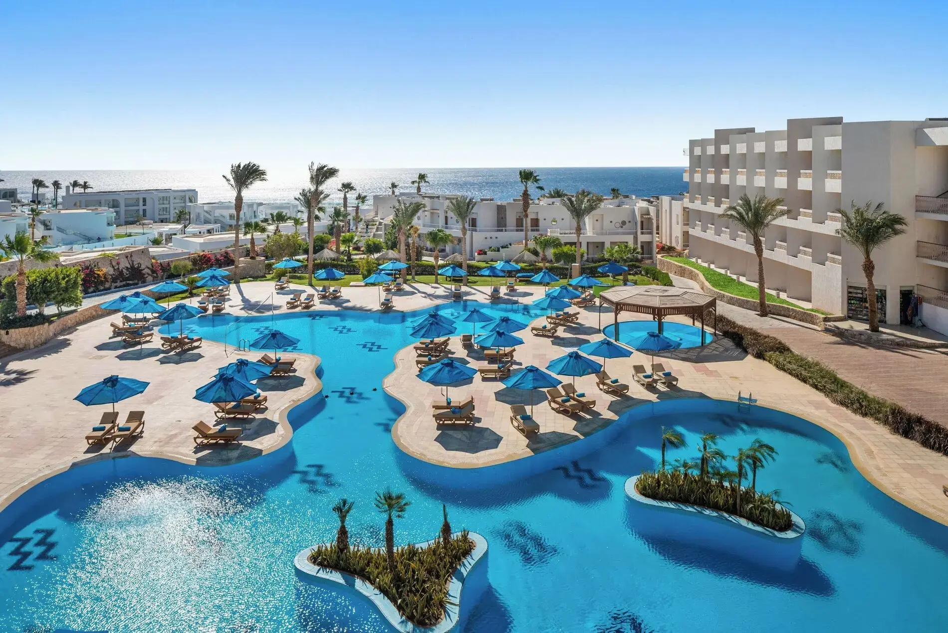 Басейни с острови от палми и сини чадъри с изглед към морето – DoubleTree by Hilton Sharks Bay Resort, Шарм Ел Шейх