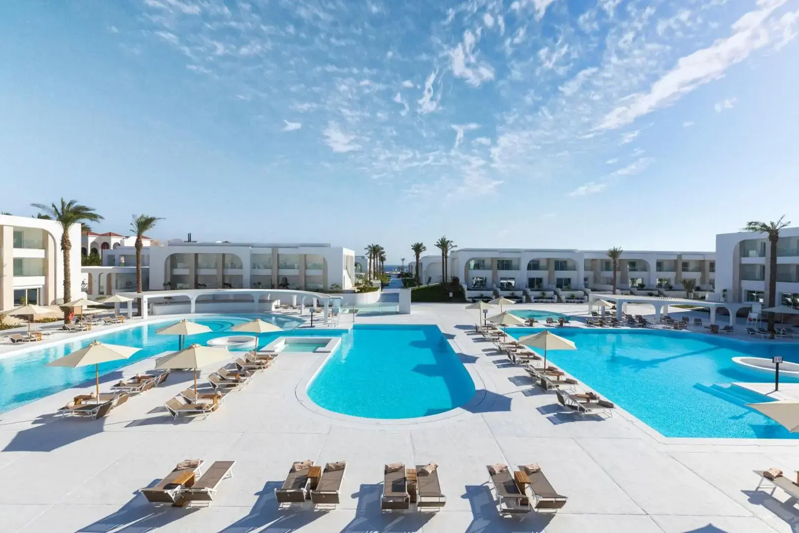 Басейни с чадъри пред двуетажните корпуси под синьо небе – Posh Club - Sunrise White Hills Resort, Шарм Ел Шейх